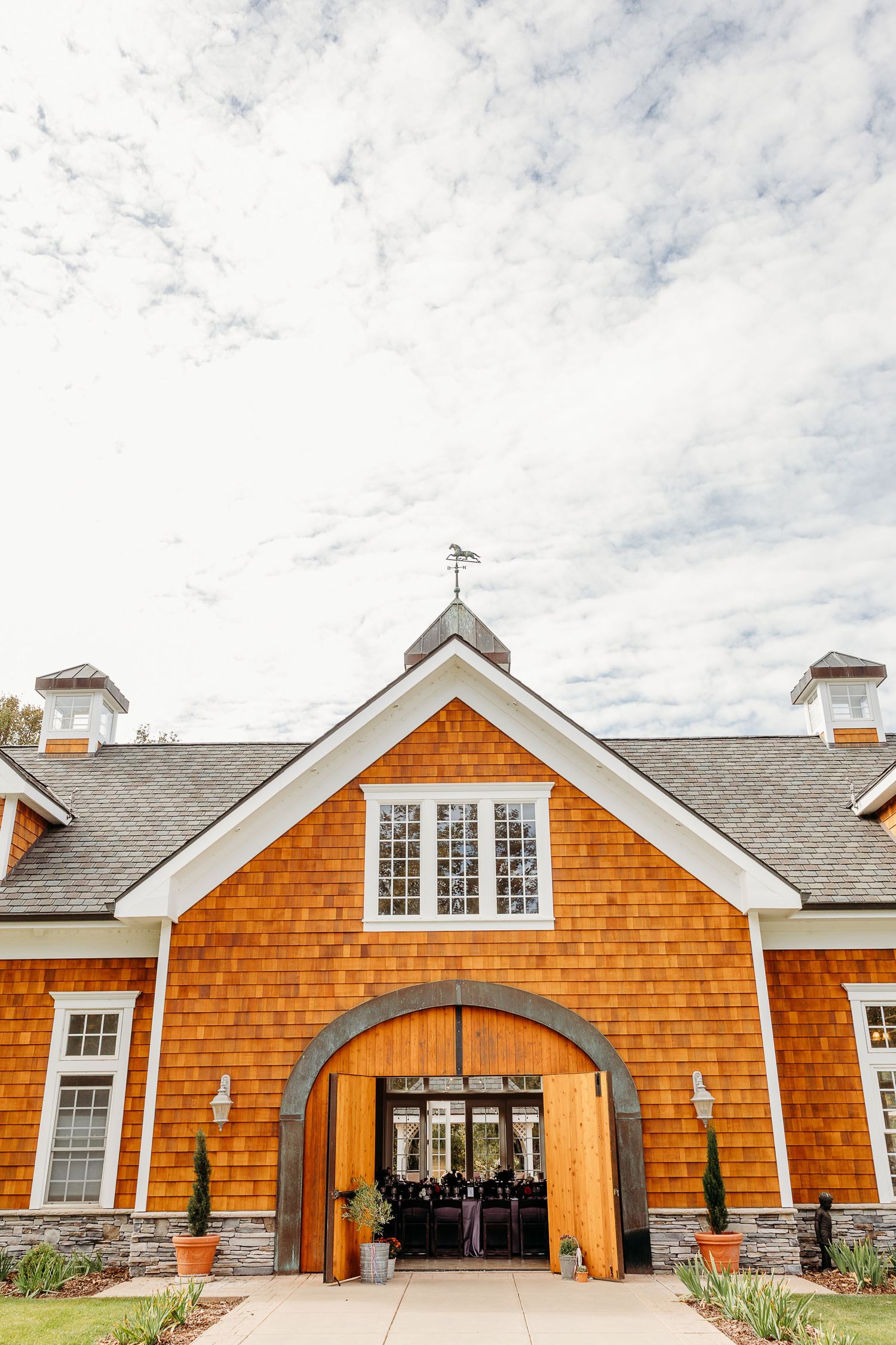 Orange cedar shake church building with white trim and arched entrance under cloudy sky.