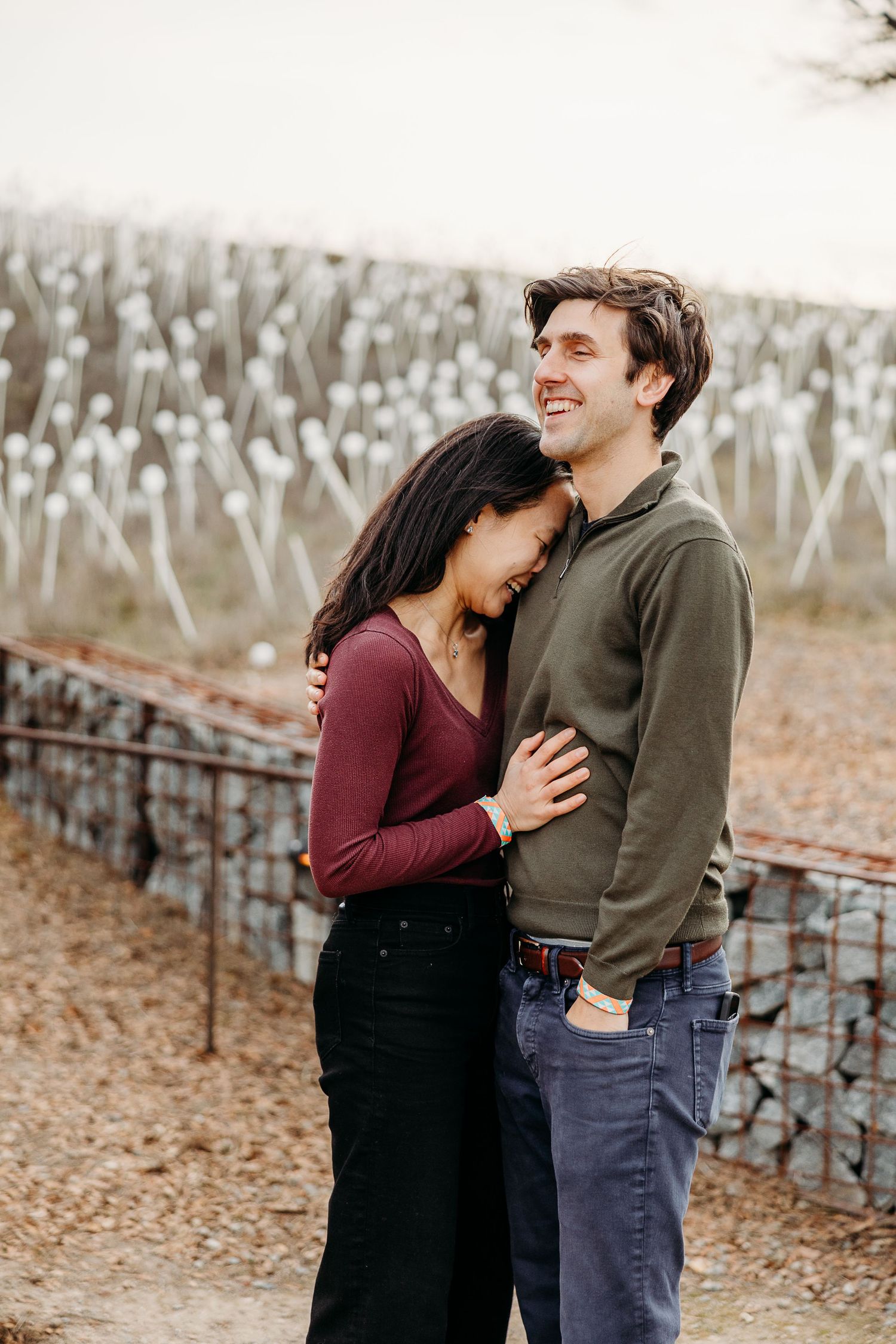 A couple shares an intimate embrace in front of a vineyard during autumn.