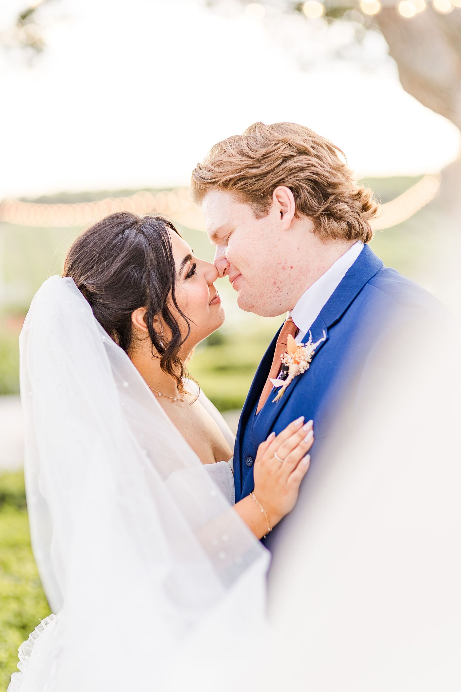 A soft, dreamy wedding portrait shows a tender moment between newlyweds.