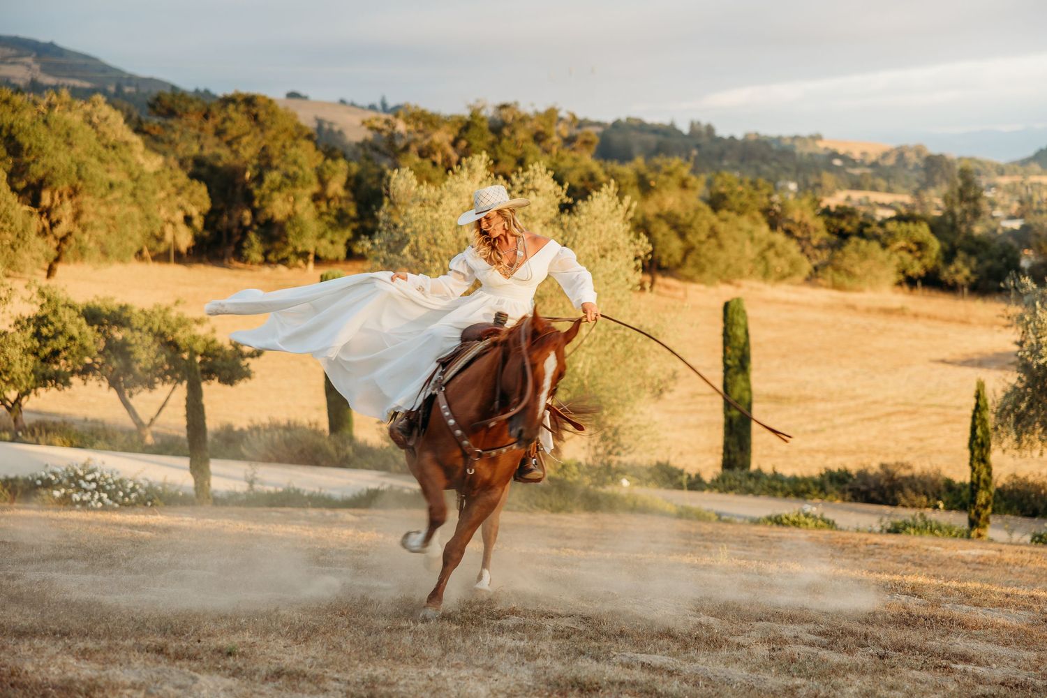 Dynamic action shot of horseback riding on a dusty mountain trail at sunset.