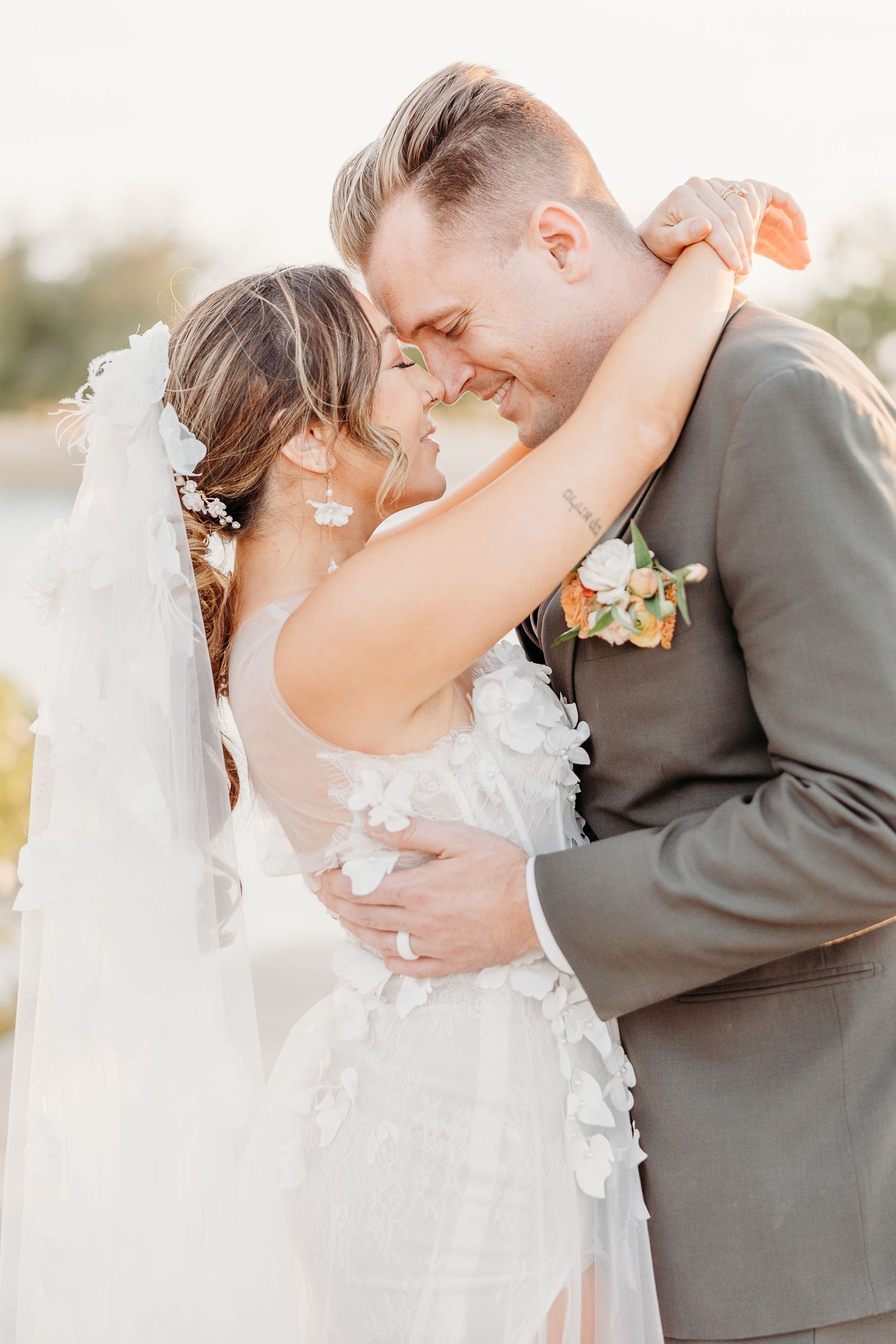 Newlyweds share an intimate moment during their wedding photoshoot at sunset.