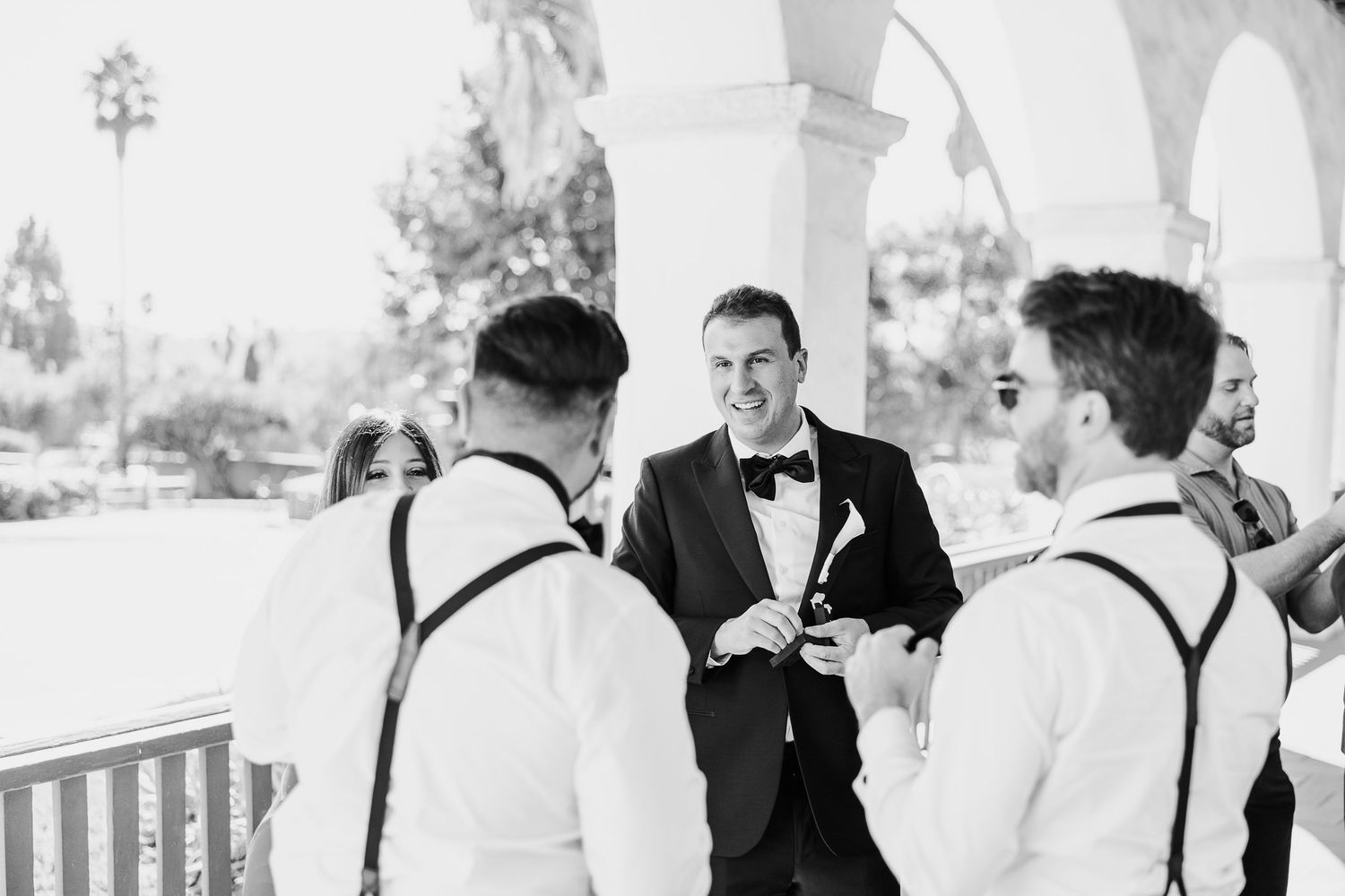 A series of black and white wedding photos showing candid moments between guests and the wedding party at an outdoor venue.