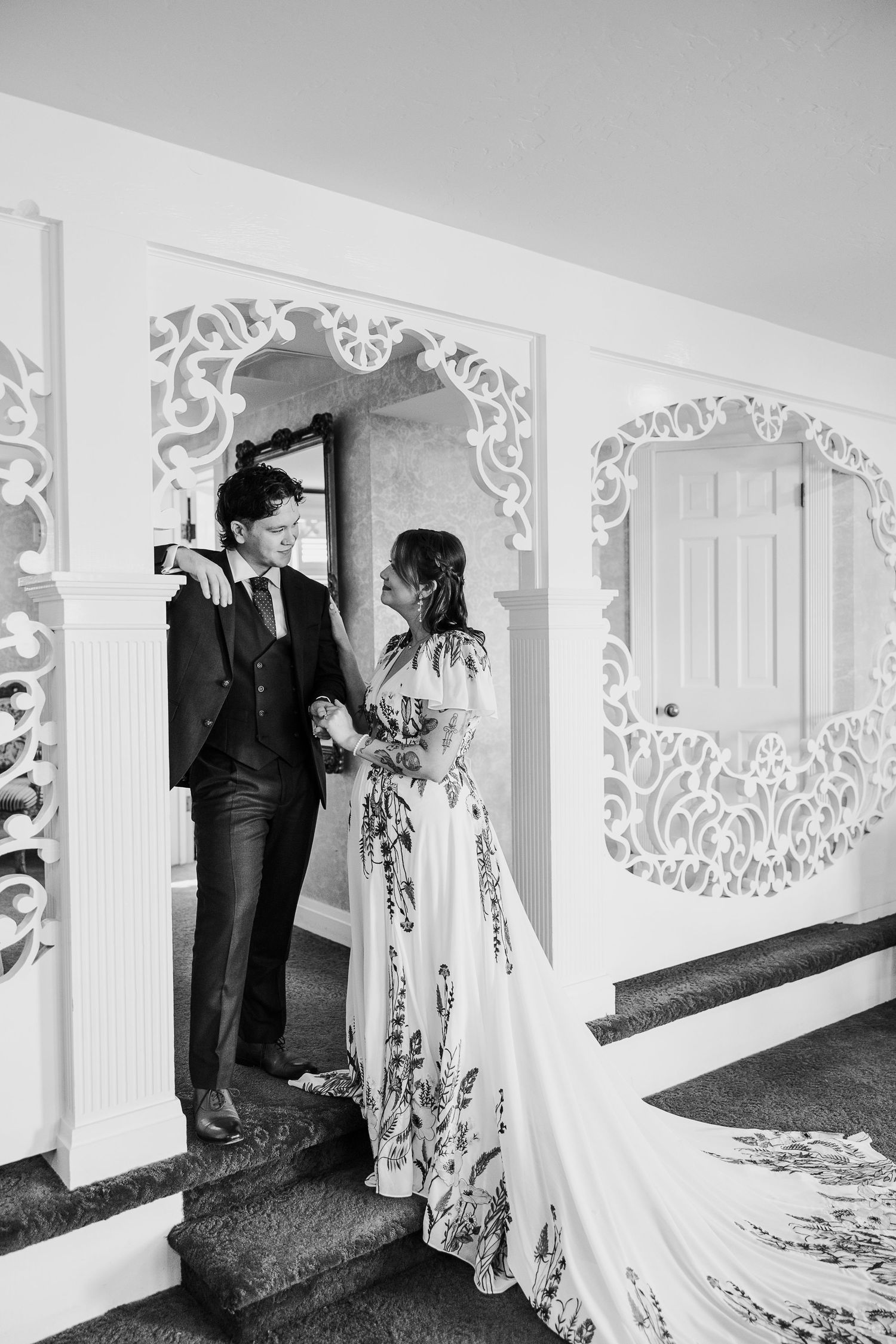 Black and white wedding photo showing an ornate white archway with decorative details.
