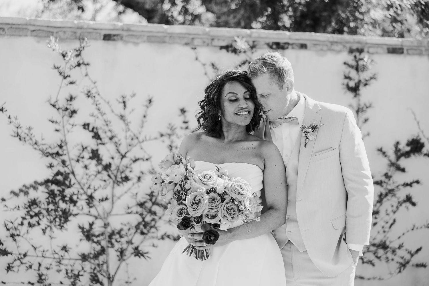 Black and white wedding portraits showing tender moments between newlyweds against a garden backdrop.