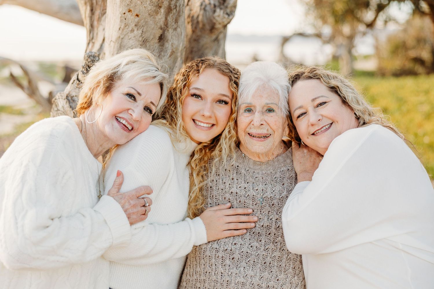 Group photo of people in white sweaters hugging and smiling together outdoors.