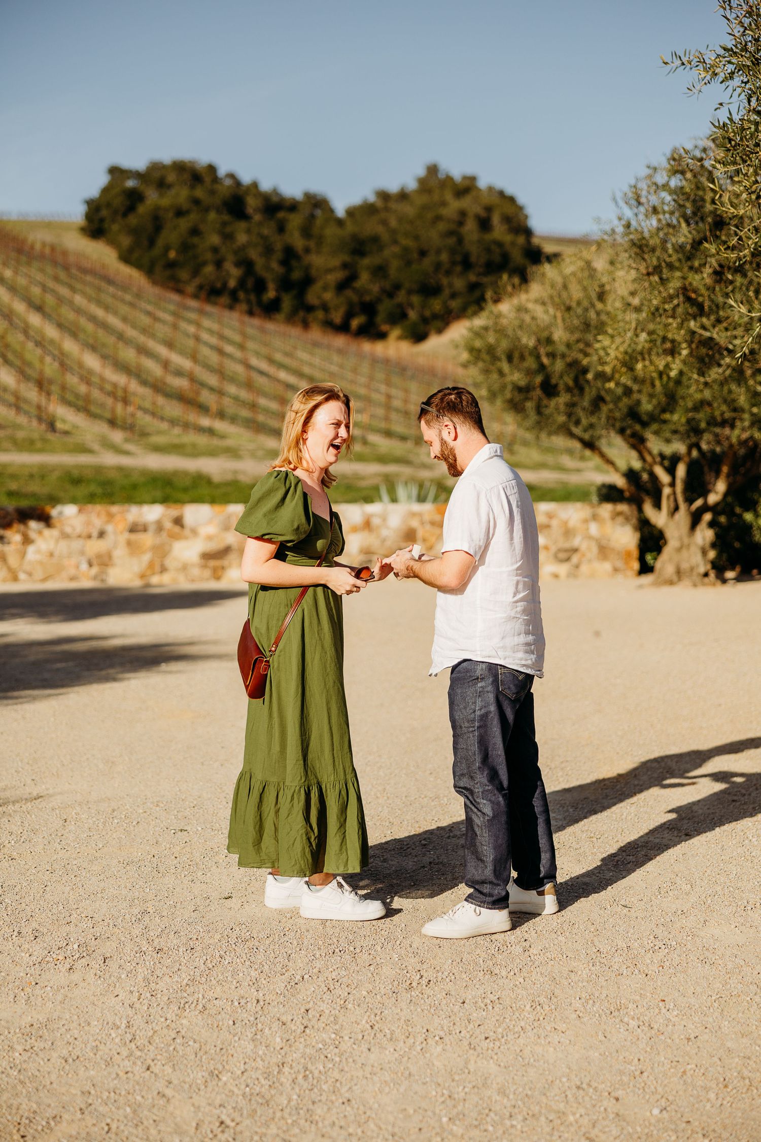 A couple sharing a special moment on a stone patio overlooking vineyard rows.