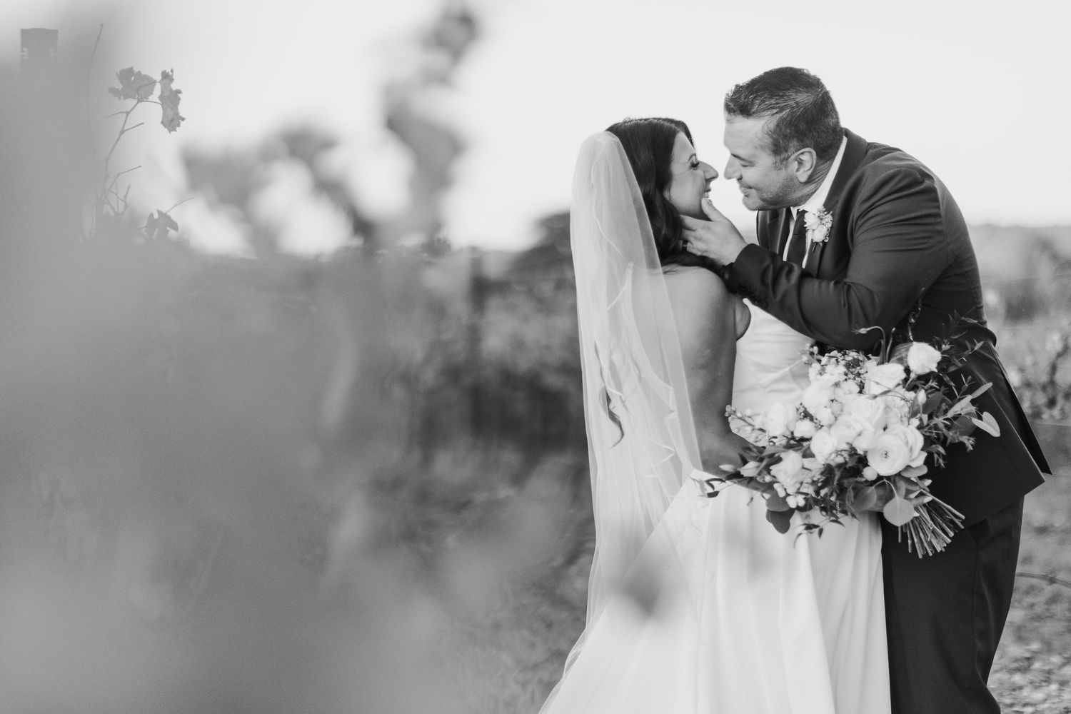Black and white romantic wedding portrait with a soft focus floral foreground.