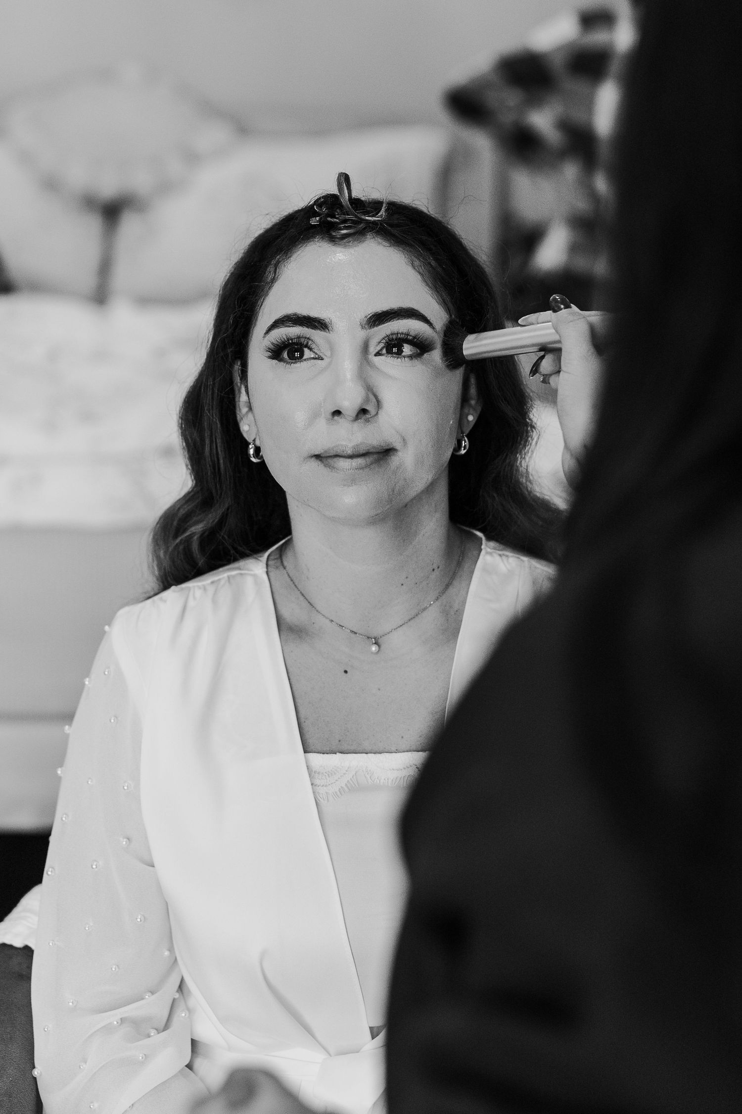 Getting ready scene with makeup application in black and white photography.