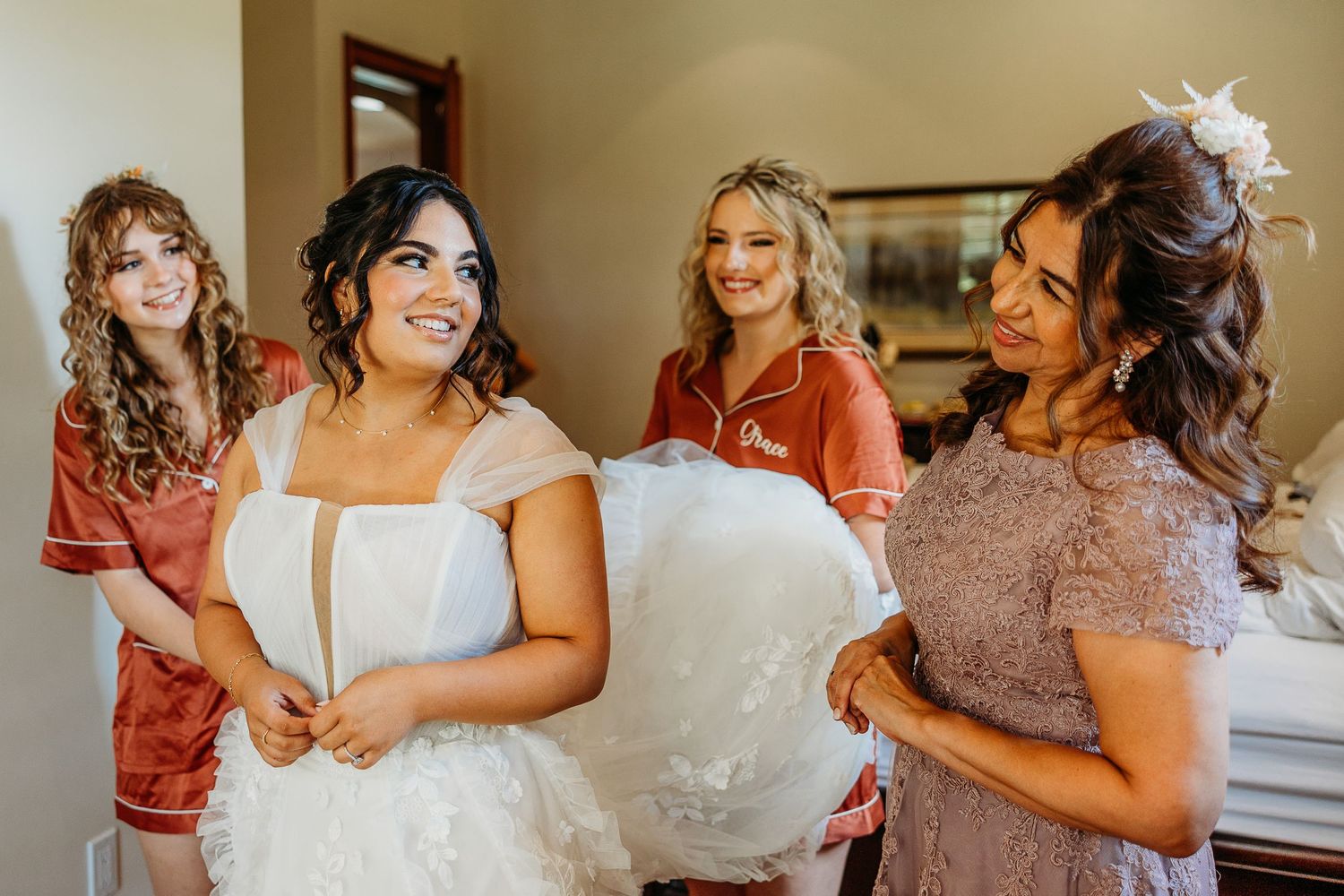A joyful getting ready moment shared between friends in pastel dresses preparing for a special occasion.