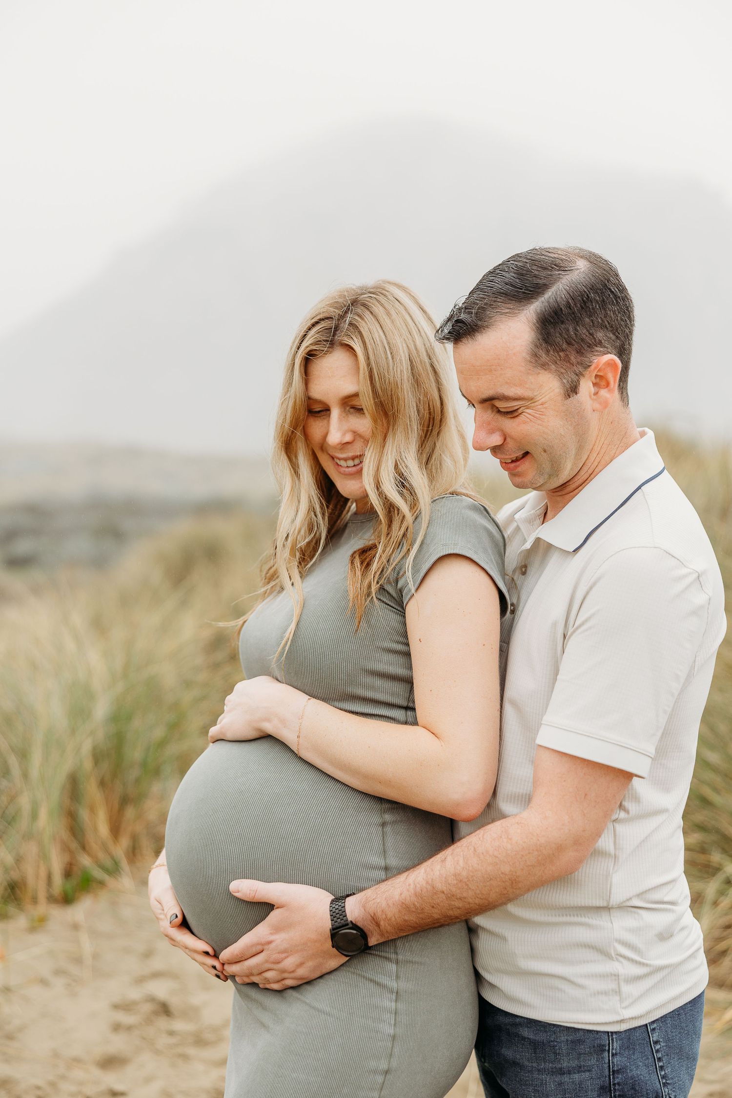 Intimate maternity portrait of a couple in a field with coastal grasses.