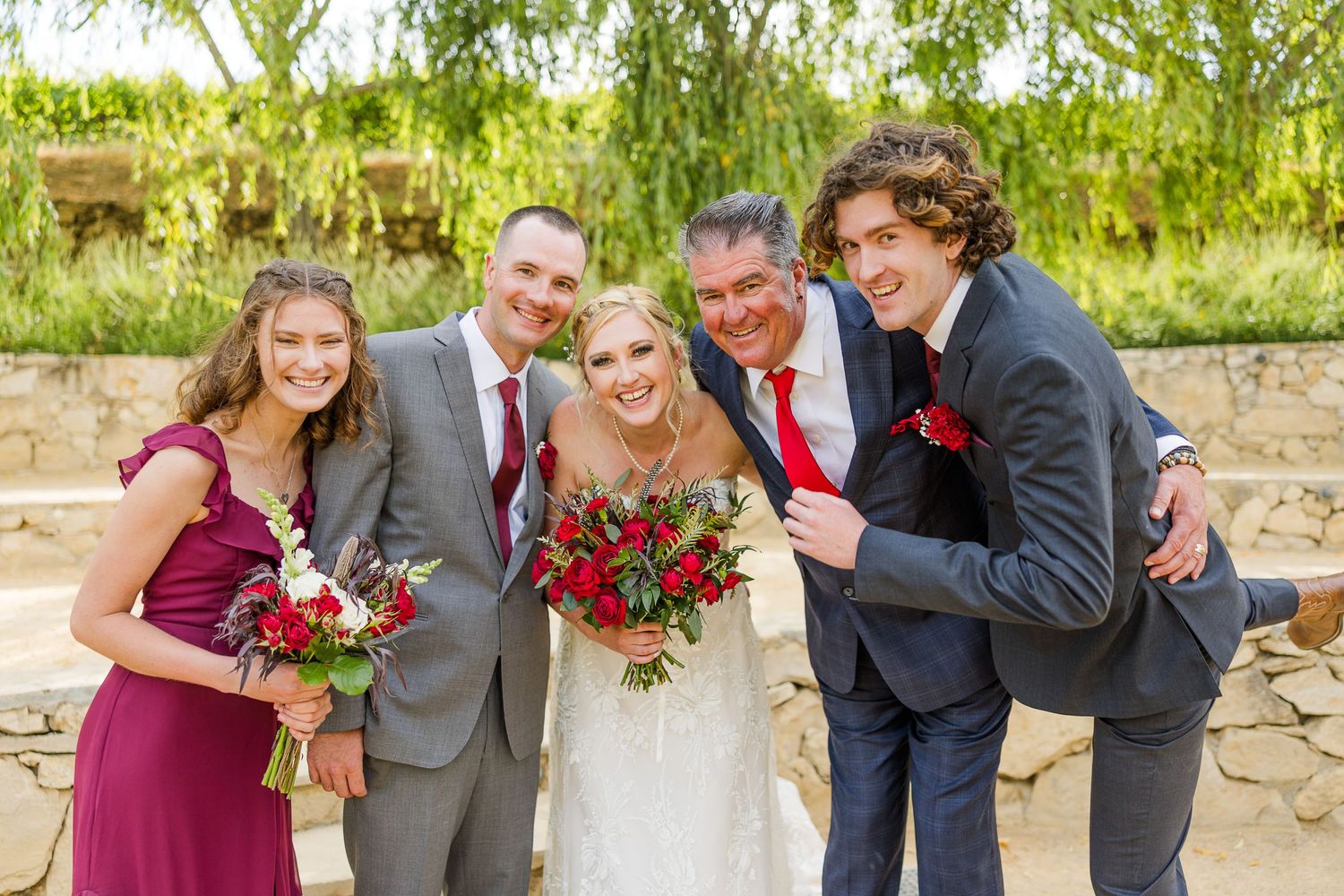 Intimate group portrait with burgundy and gray attire against natural backdrop.
