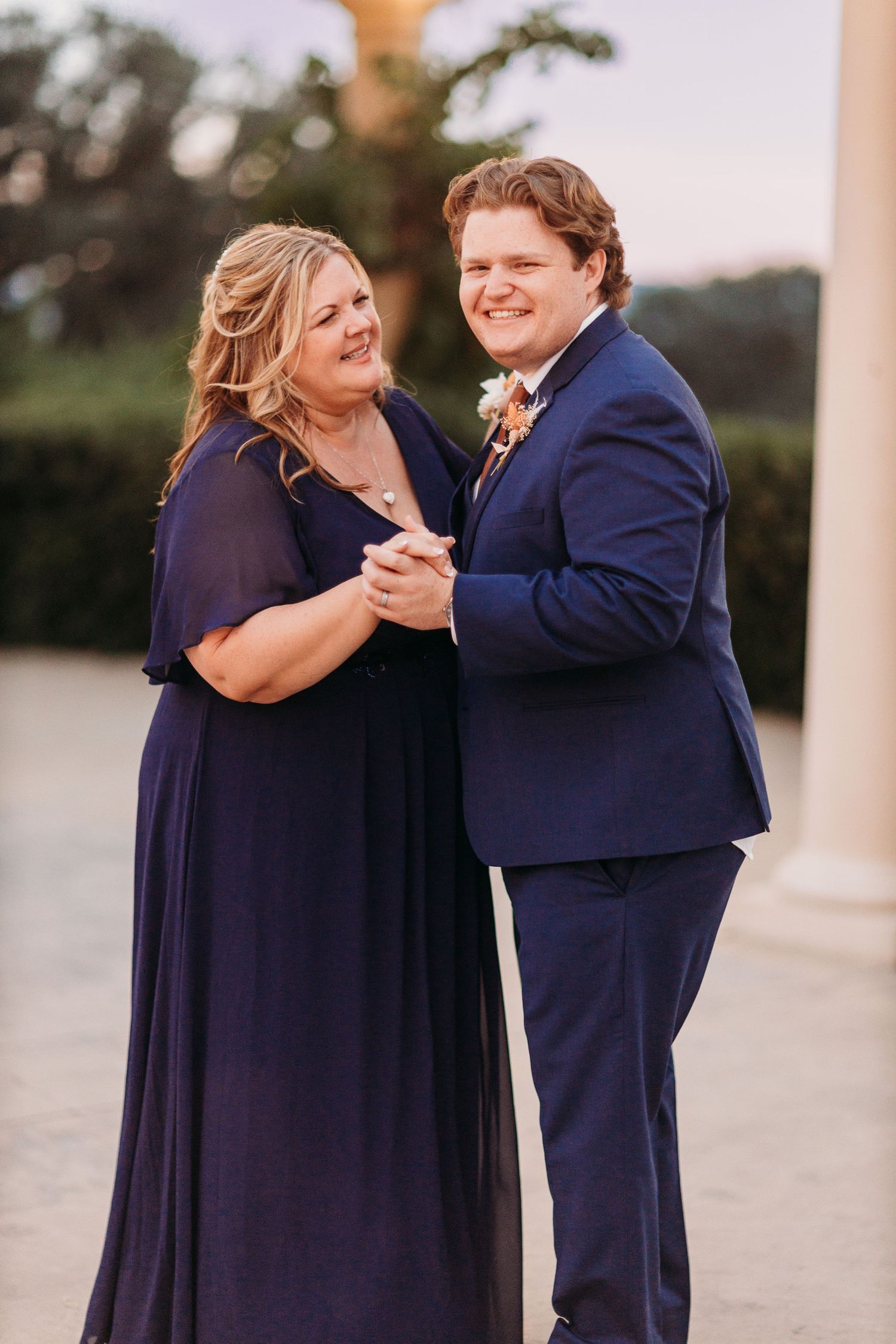 A couple in matching navy outfits share a dance while smiling joyfully.