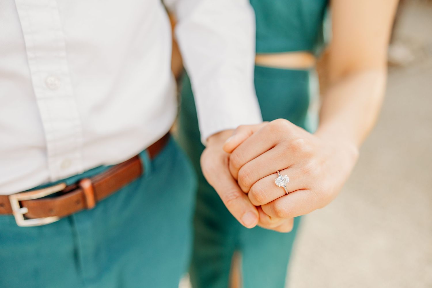 Hands wearing engagement ring shown in sequence against teal and white background.