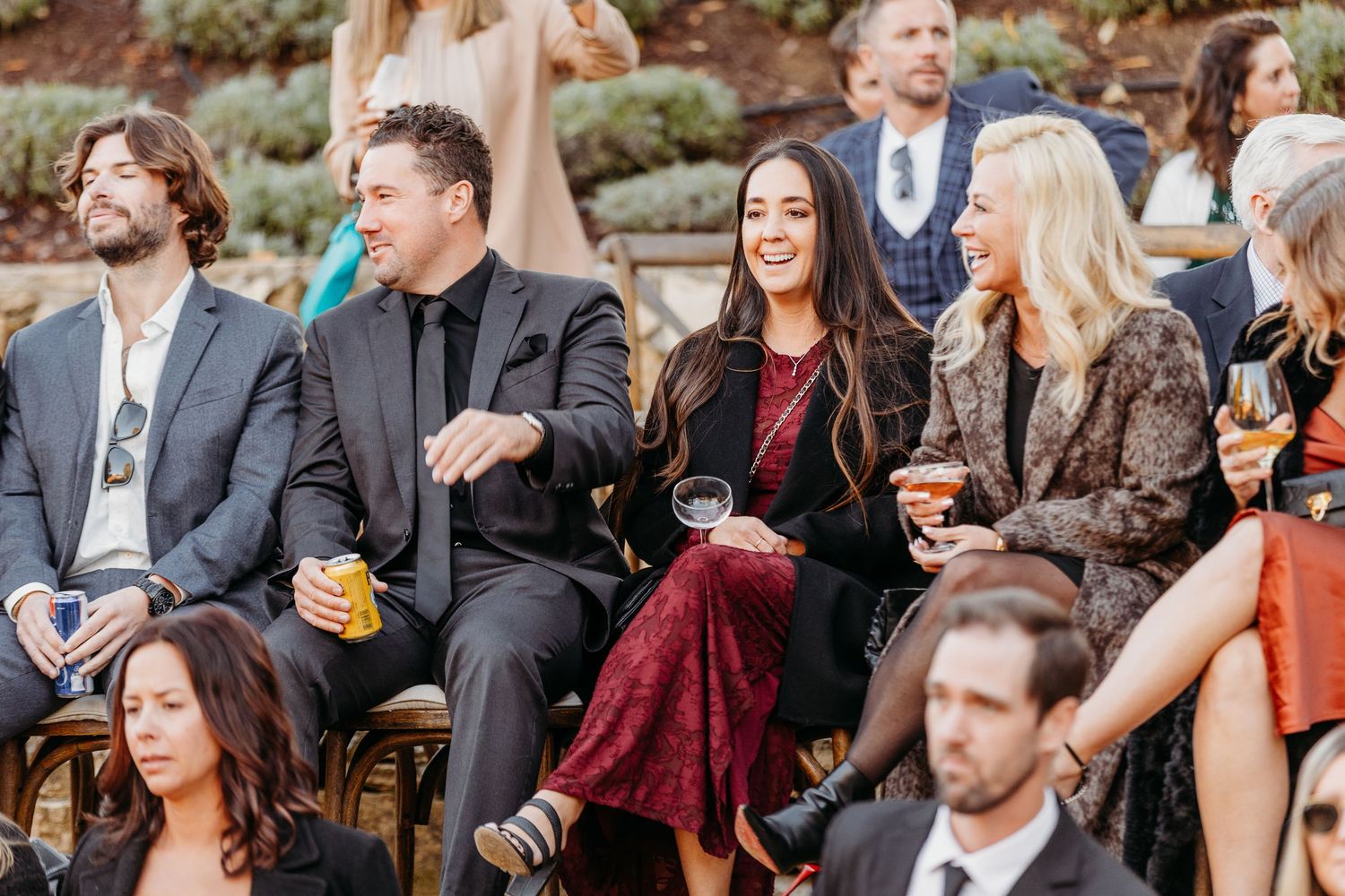 Wedding guests seated outdoors watching ceremony with joyful expressions.
