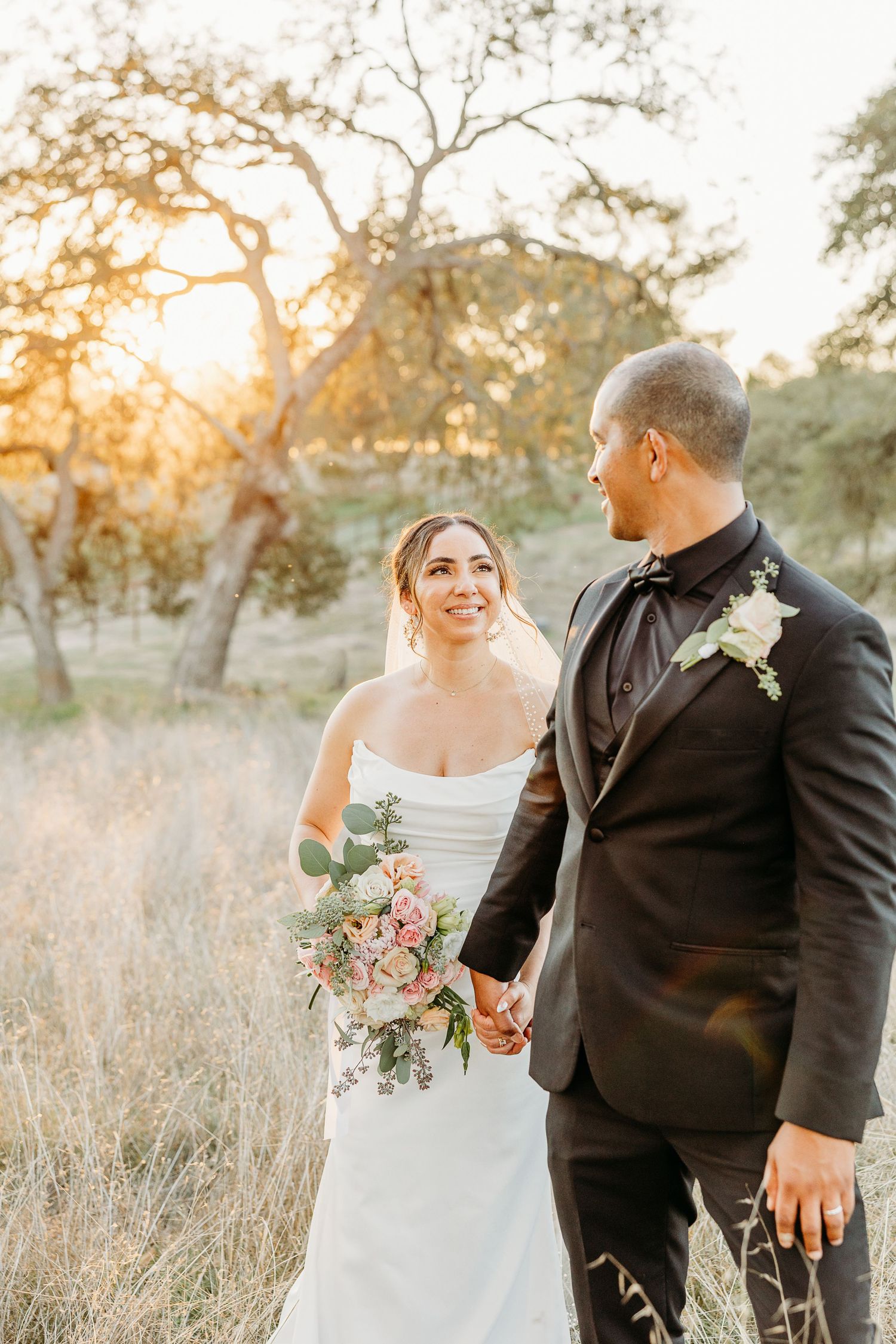 Romantic sunset wedding portrait in a golden field with soft natural lighting.