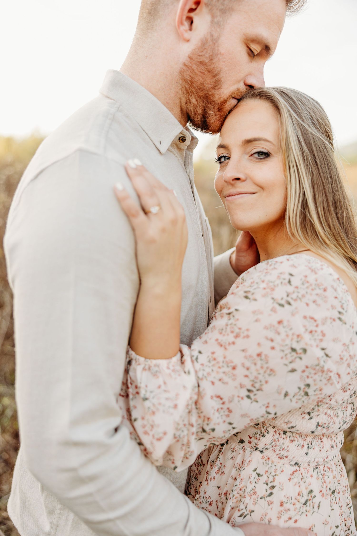 Sweet tender moment between couple in soft golden light outdoors.