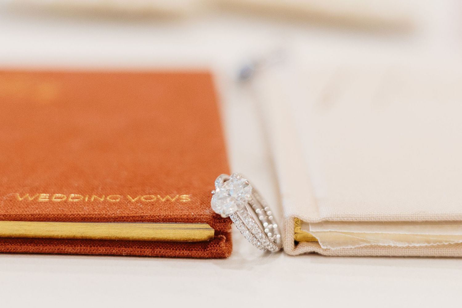 Close up of diamond engagement ring resting on brown leather wedding vow book.