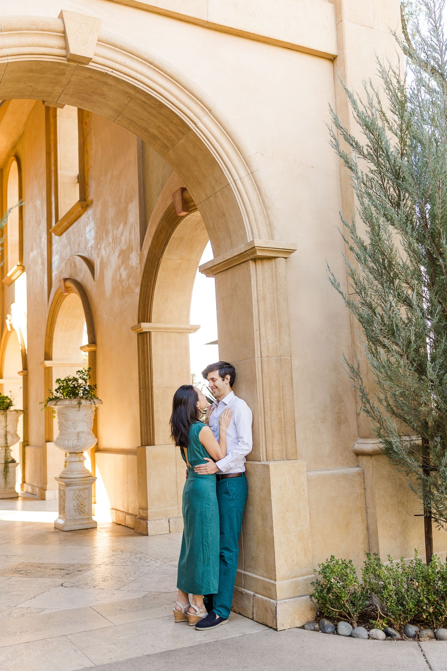 A romantic moment captured under stone archways in a sunlit Mediterranean courtyard.