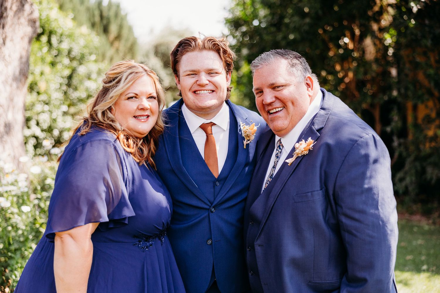Wedding party photo featuring formal attire in navy blue and orange accent colors.