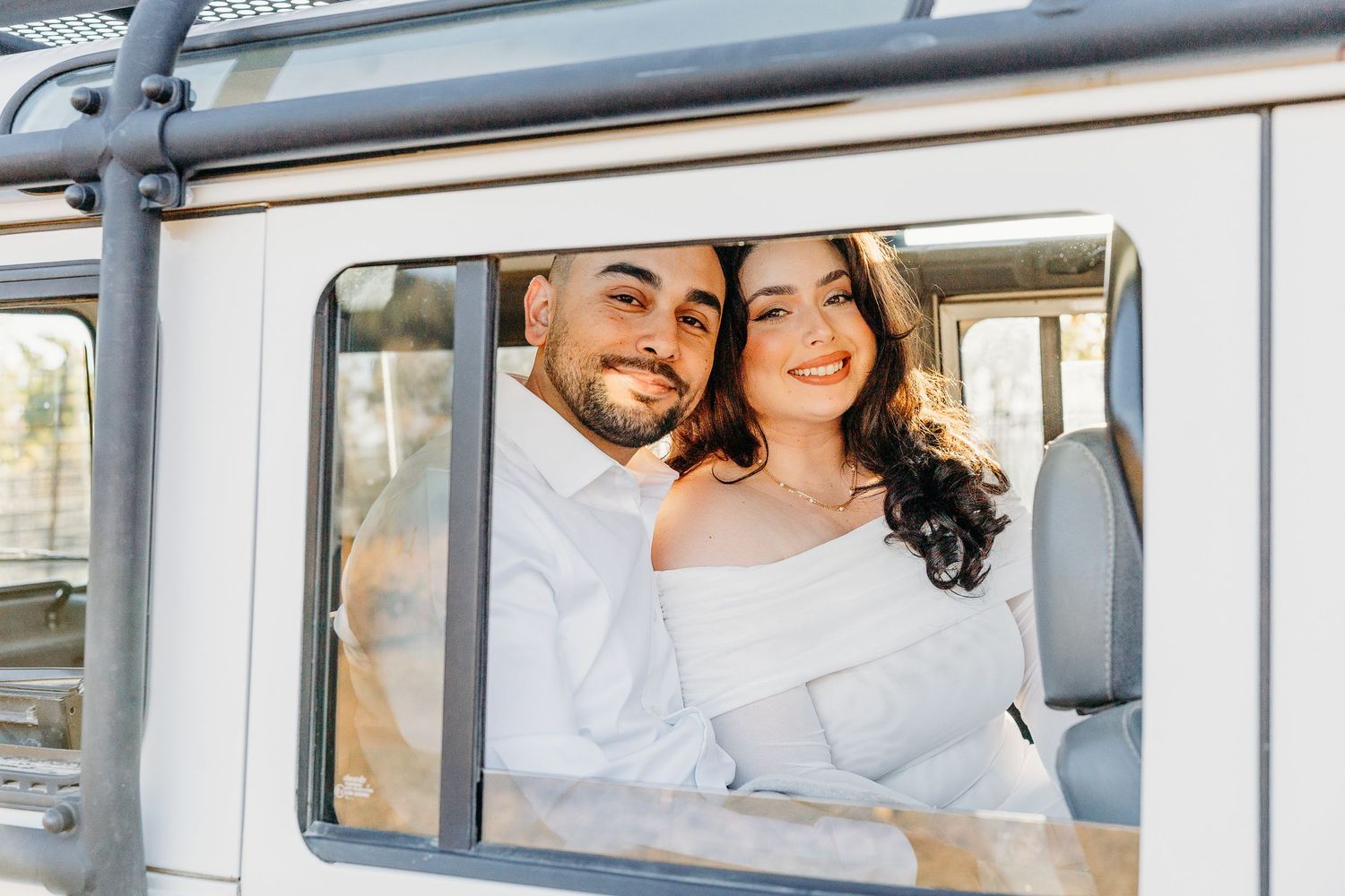 Happy couple smiles through the window of a vintage van on a sunny day.
