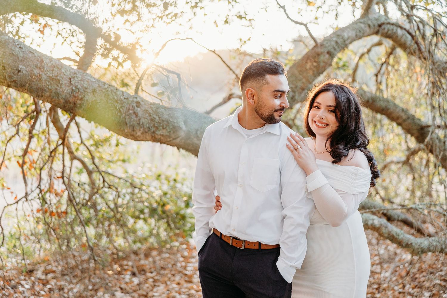 A couple dances and laughs together under autumn trees with golden leaves.