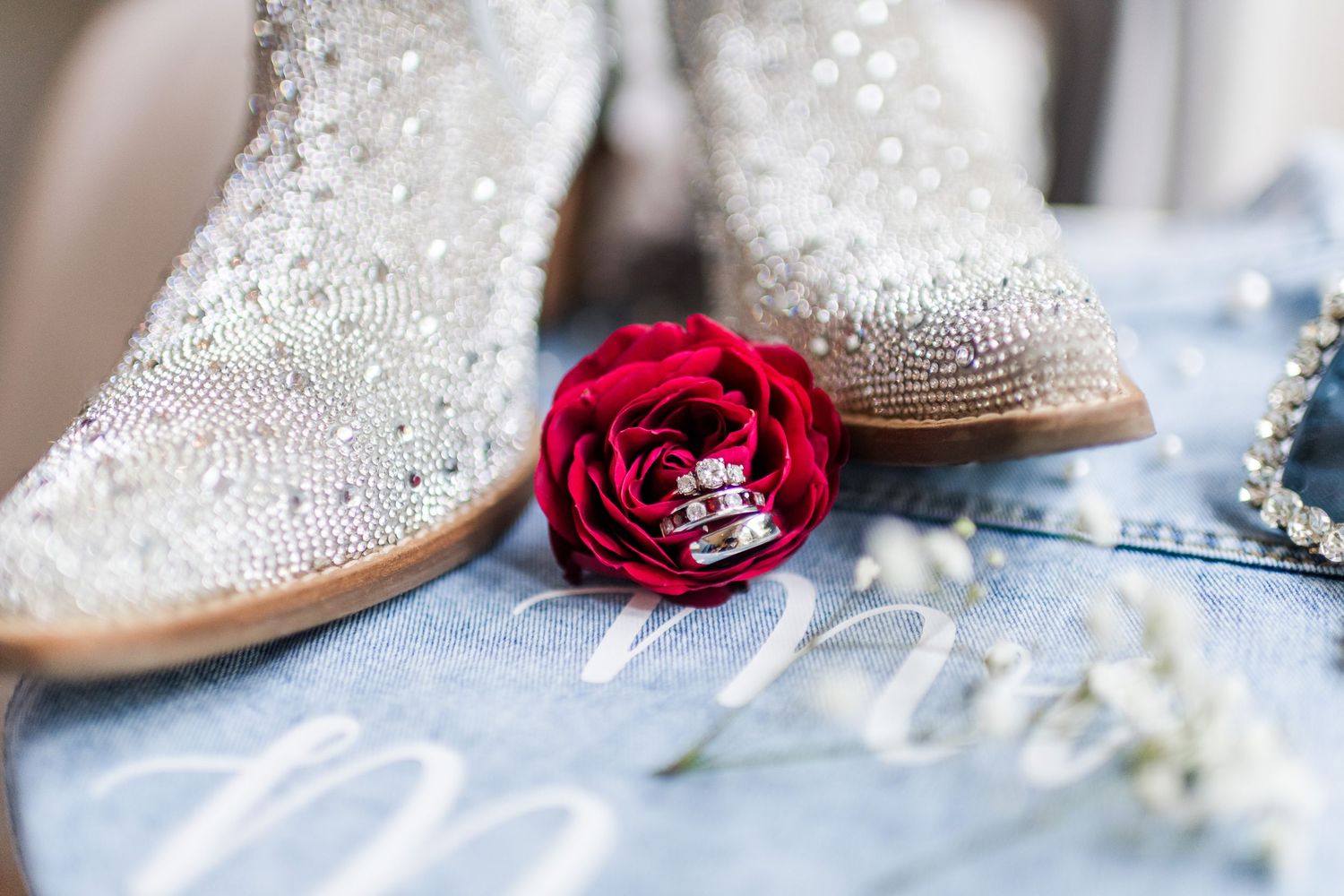 Sparkly wedding boots with a red rose detail on denim fabric.