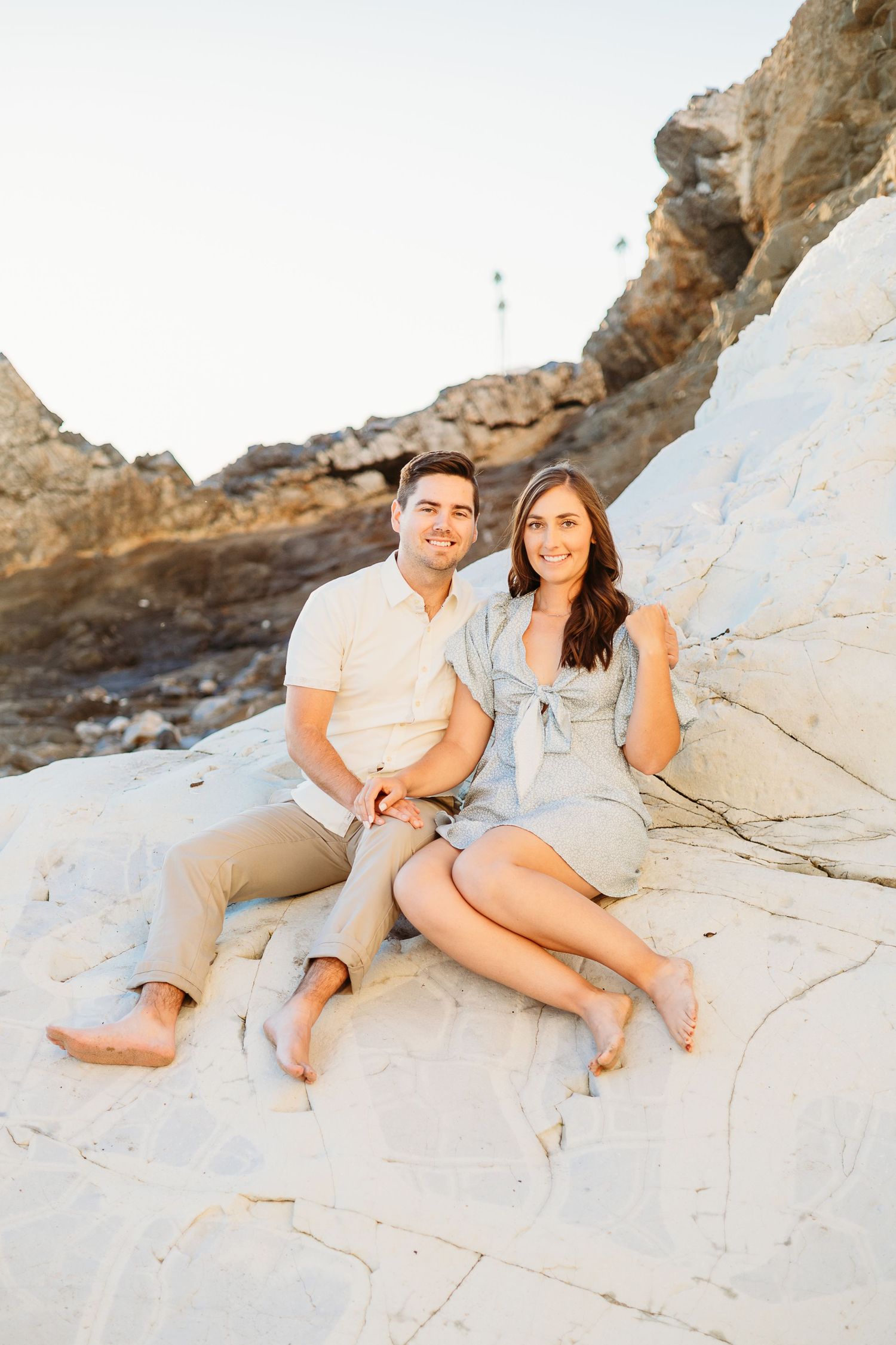A couple poses on white rocky terrain during a sunny outdoor photoshoot.