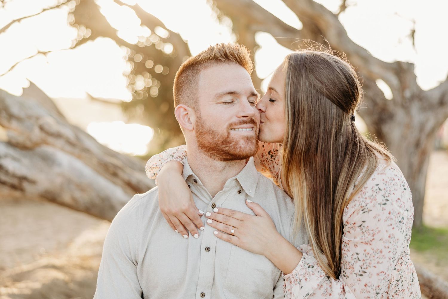 Romantic moment shared between couple with sun flare and natural scenery.