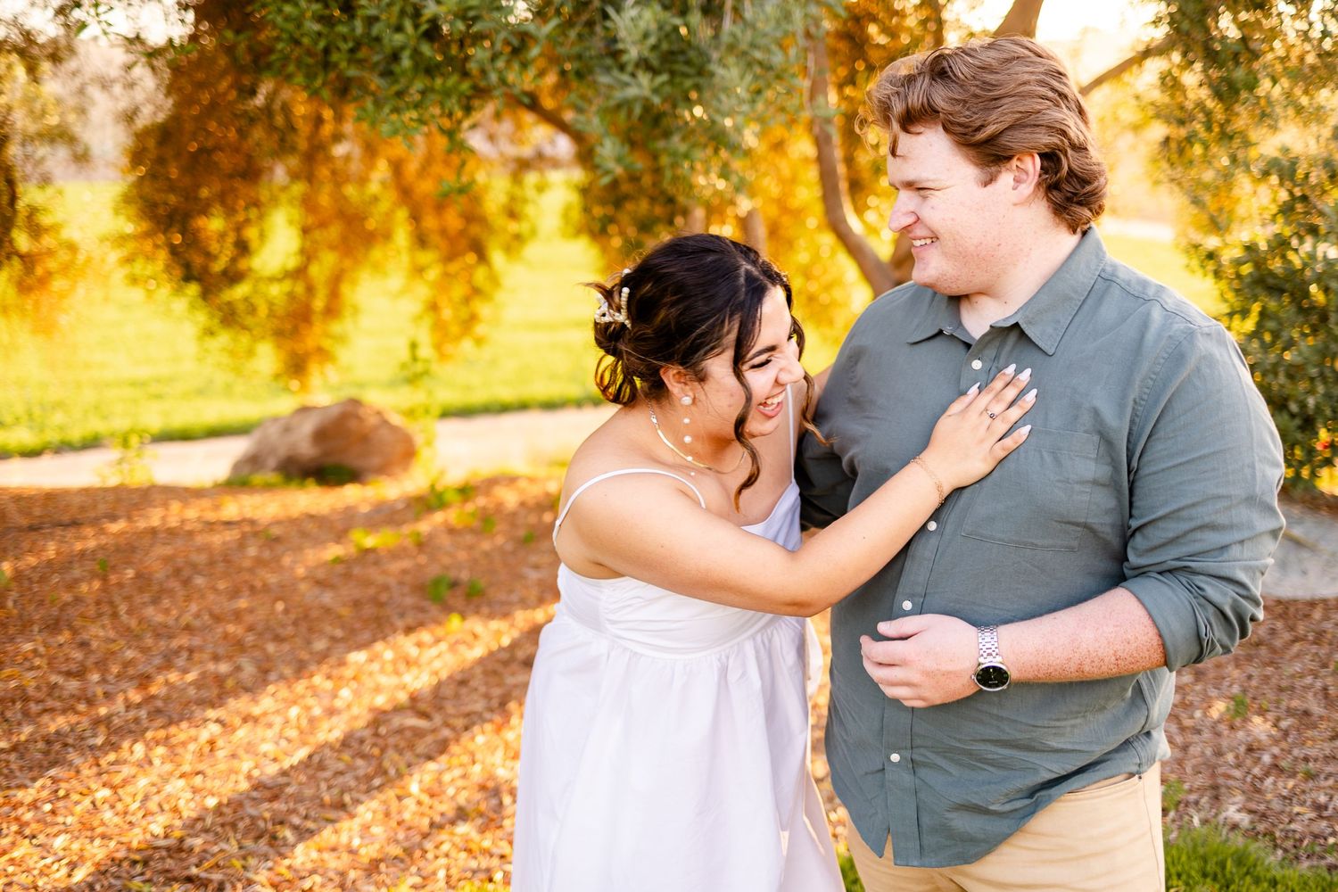 A couple shares a joyful moment together in a garden during sunset.