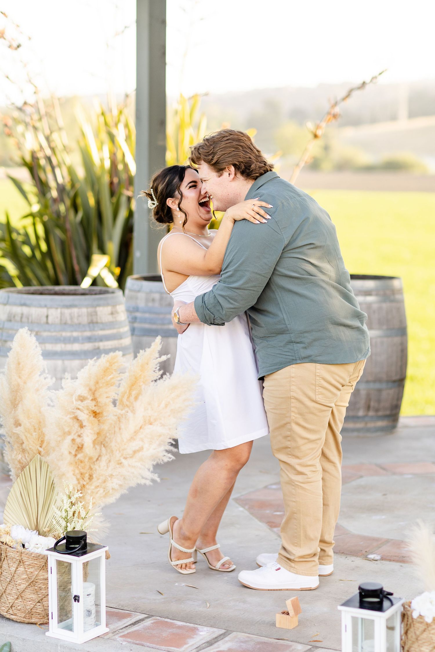 A joyful embrace shared under a gazebo decorated with pampas grass and lanterns at golden hour.