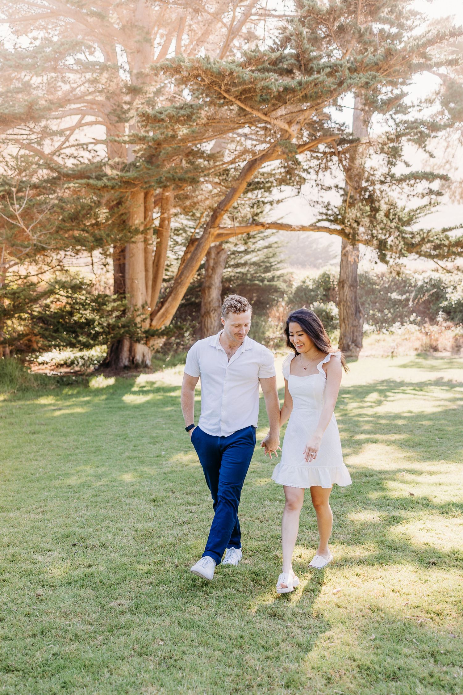 Couple in coordinated outfits walking together through sunny park.