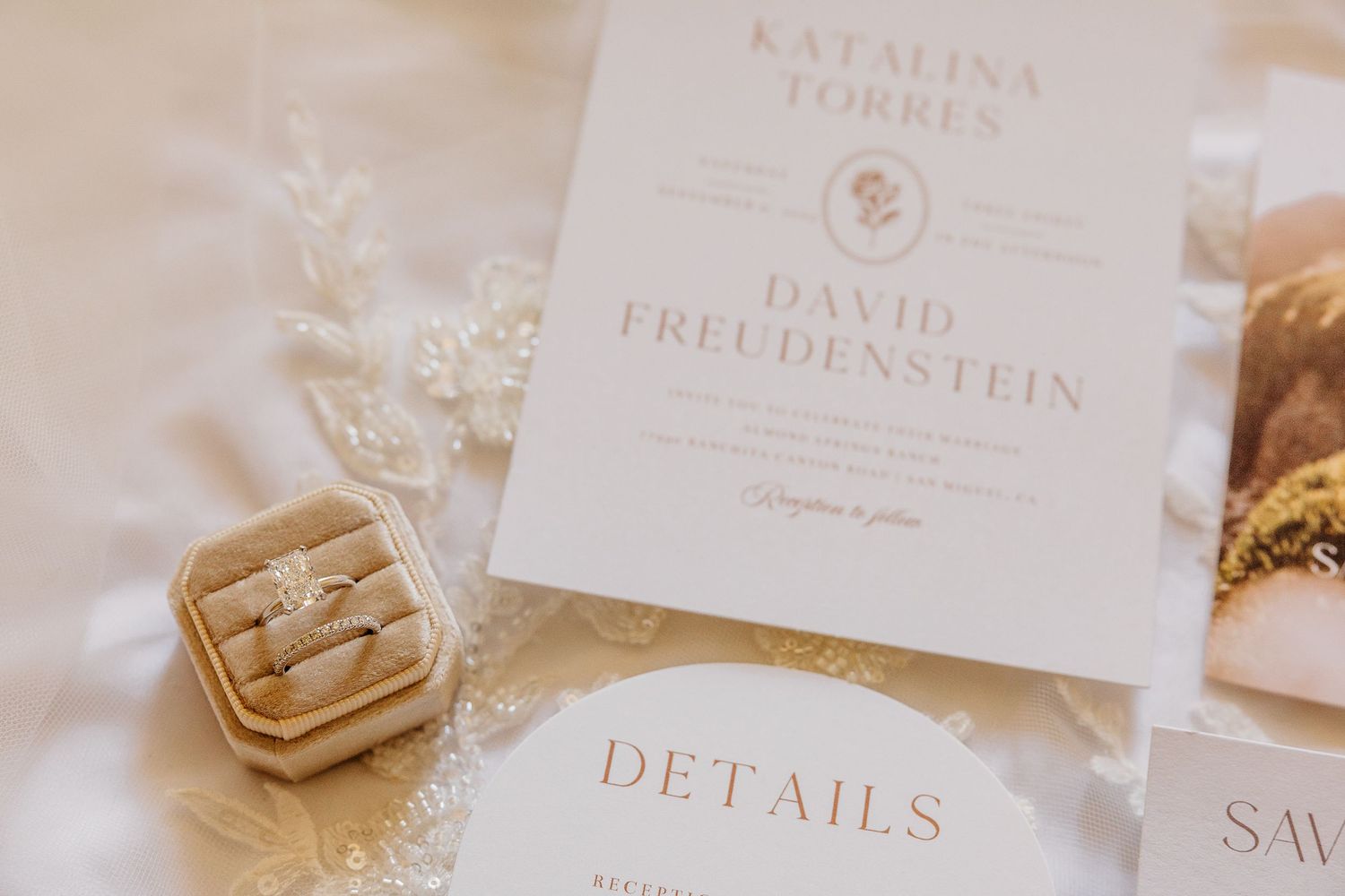 Elegant wedding invitation suite with floral details and calligraphy displayed on a light colored table.