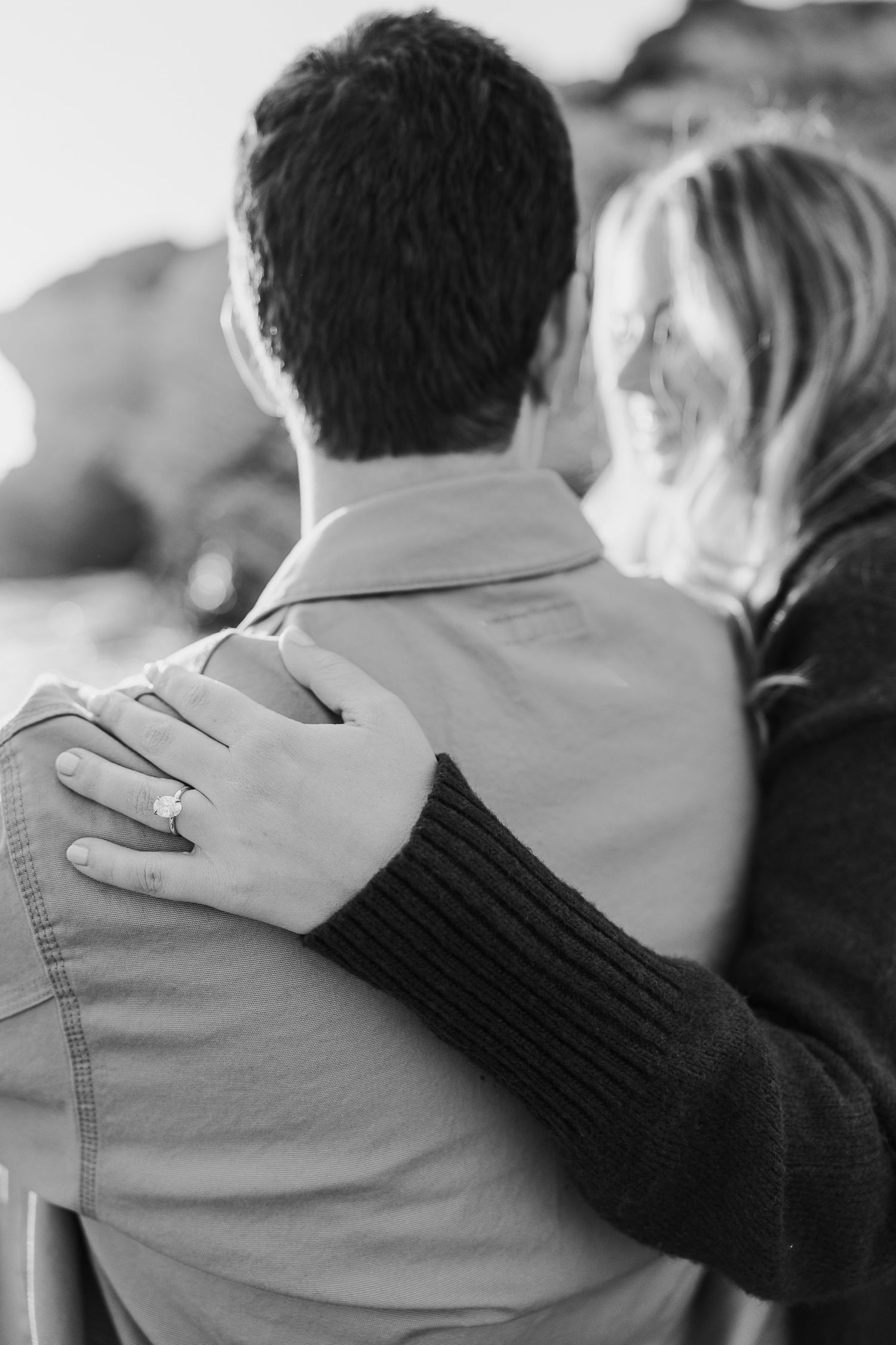 Close-up of hands resting gently on shoulders in an intimate black and white moment.