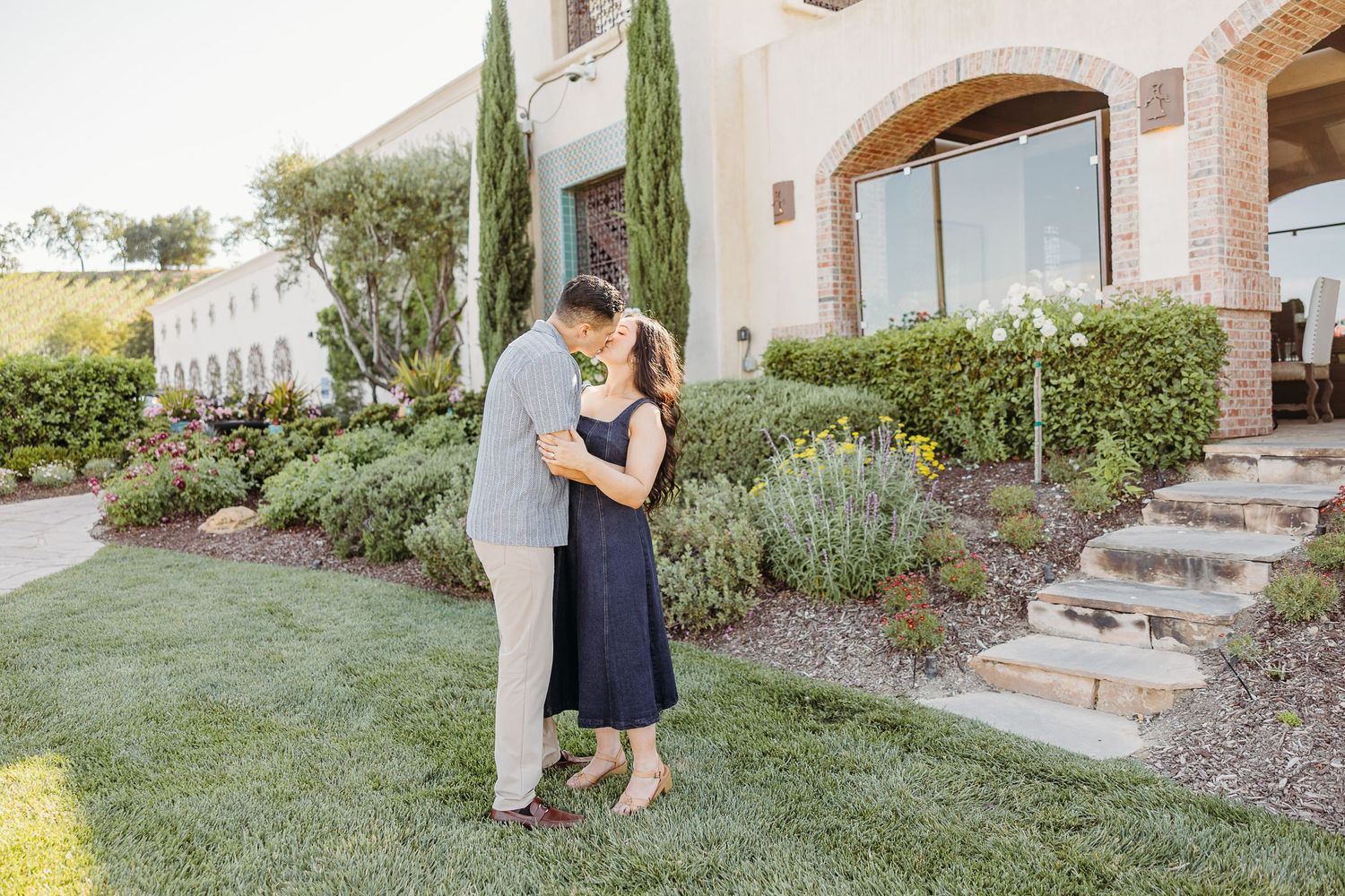 Romantic couple portraits outside a Mediterranean style home with beautiful landscaping and stone pathways.