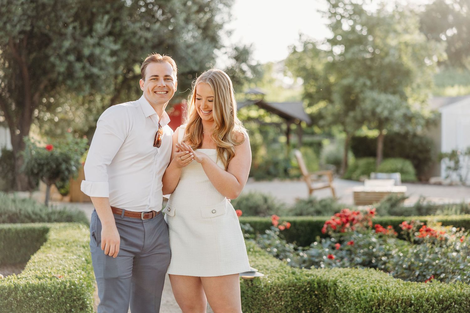 Couple shares a romantic moment in a lush garden setting during golden hour sunlight.