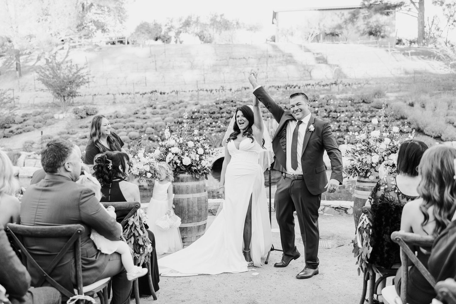 Wedding guests enjoying outdoor reception celebration in natural setting.