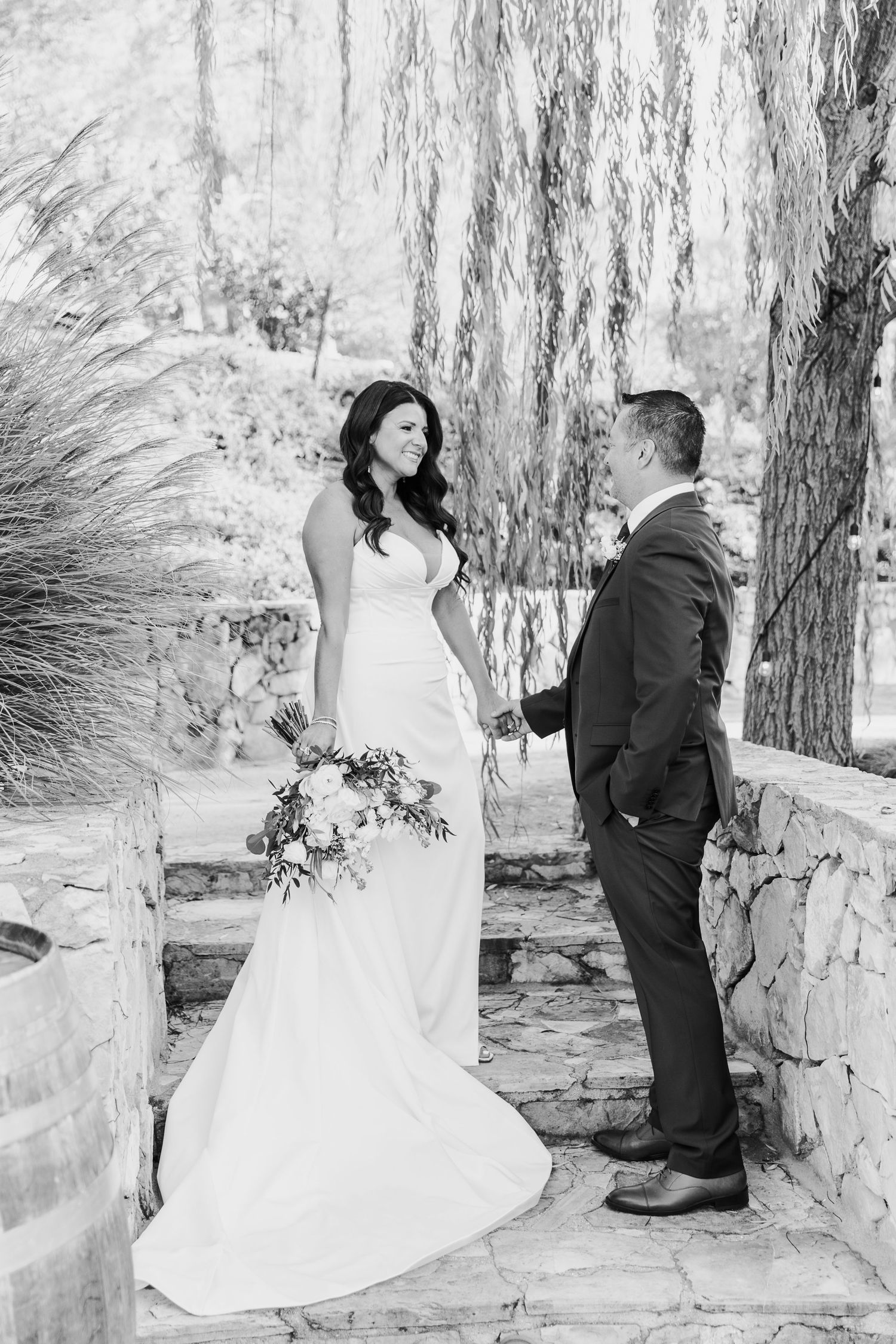 A series of black and white wedding photos showing intimate moments between a bride and groom against a stone wall.