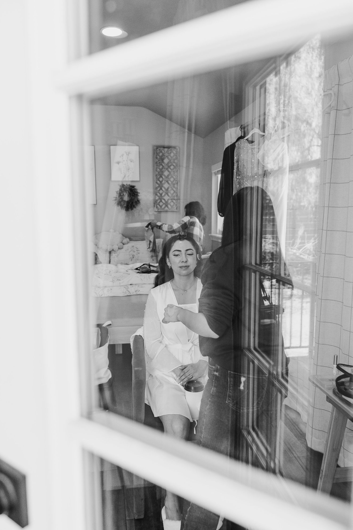 Black and white photos through window panes show a bride getting ready on her wedding day.