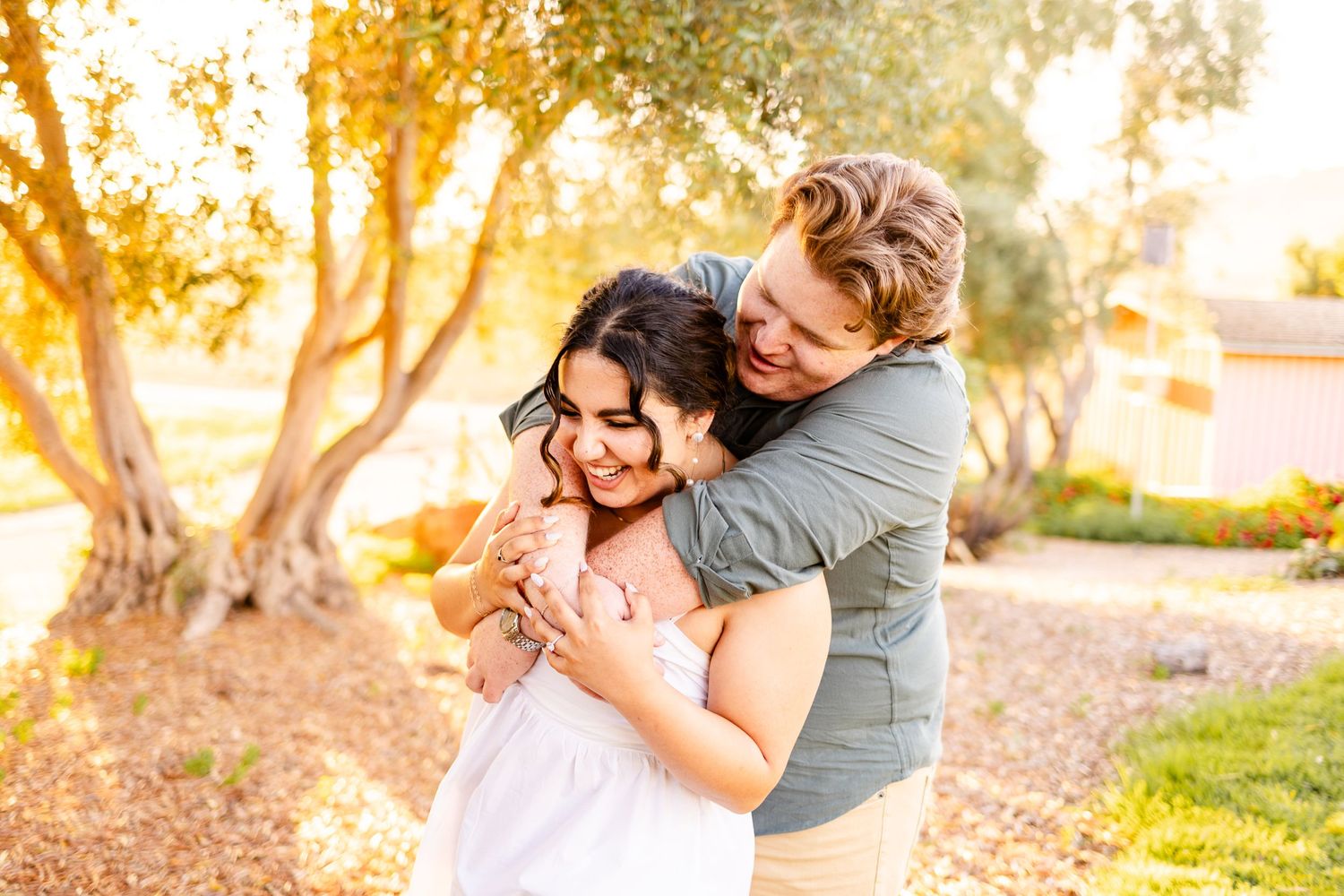 A romantic embrace captured during sunset in an outdoor garden setting.