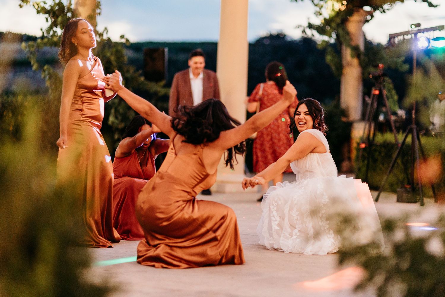 Wedding guests dance and celebrate during an outdoor evening reception.