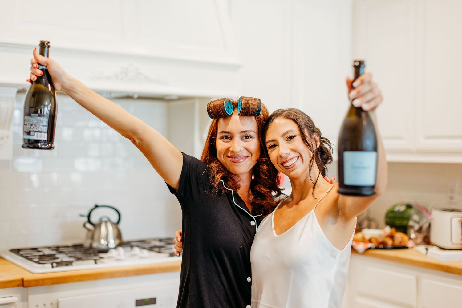 Group enjoying cocktail making and food preparation activities in a bright modern kitchen setting.