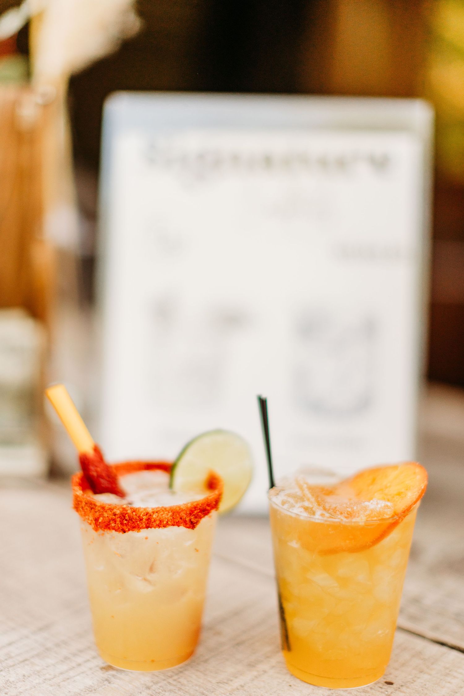 Two refreshing citrus cocktails with rimmed glasses and garnishes served on a wooden table.