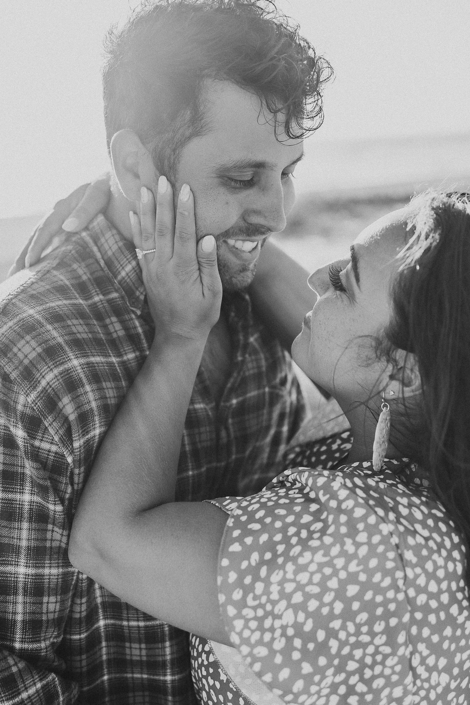 Black and white close-up of joyful couple sharing intimate moment outdoors.