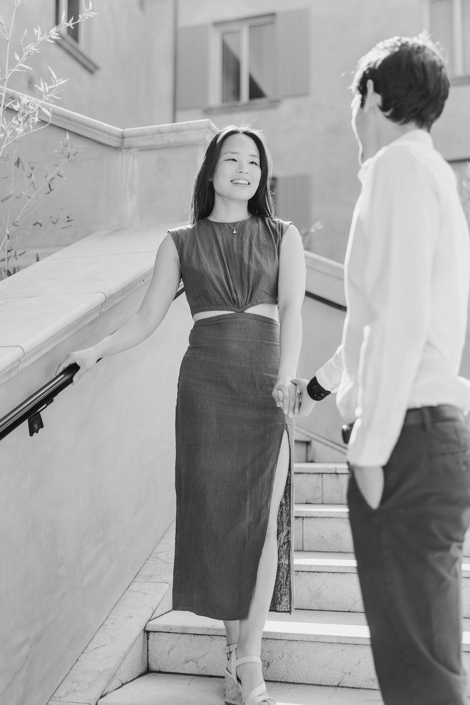 Stylish couple engaged in conversation on outdoor steps, captured in elegant black and white photography.