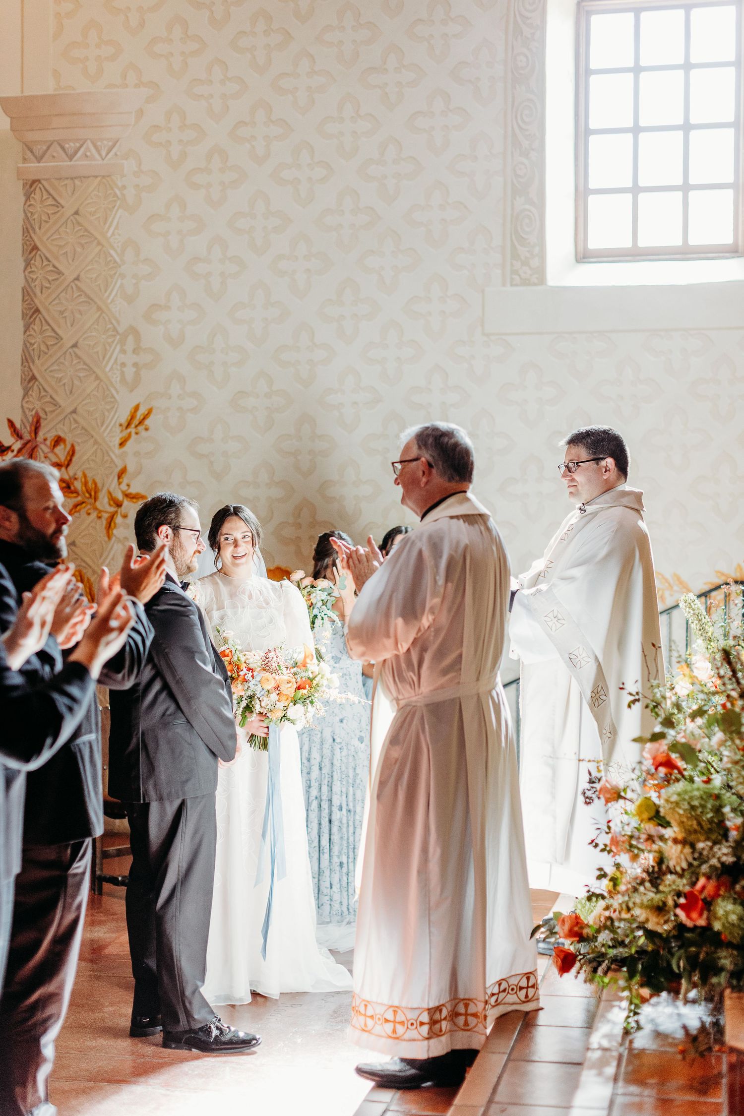 Wedding ceremony participants applaud during traditional religious service in the SLO Mission