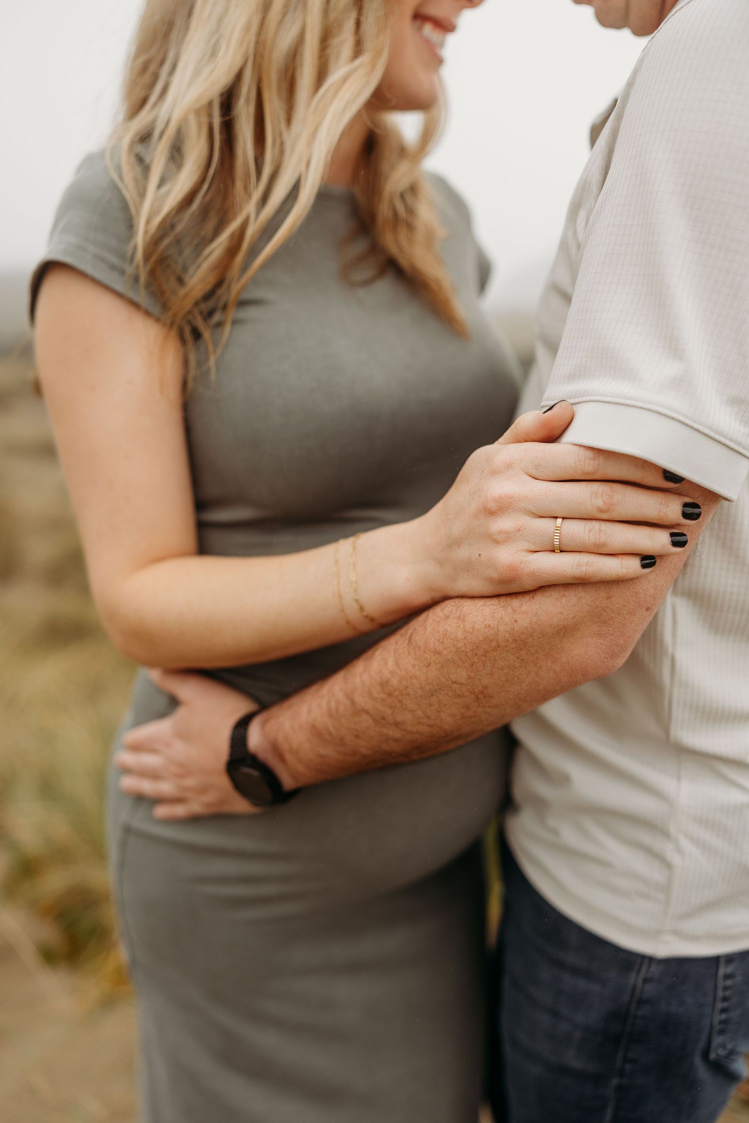 Close-up shot of an expecting couple's tender embrace showing hands and baby bump.