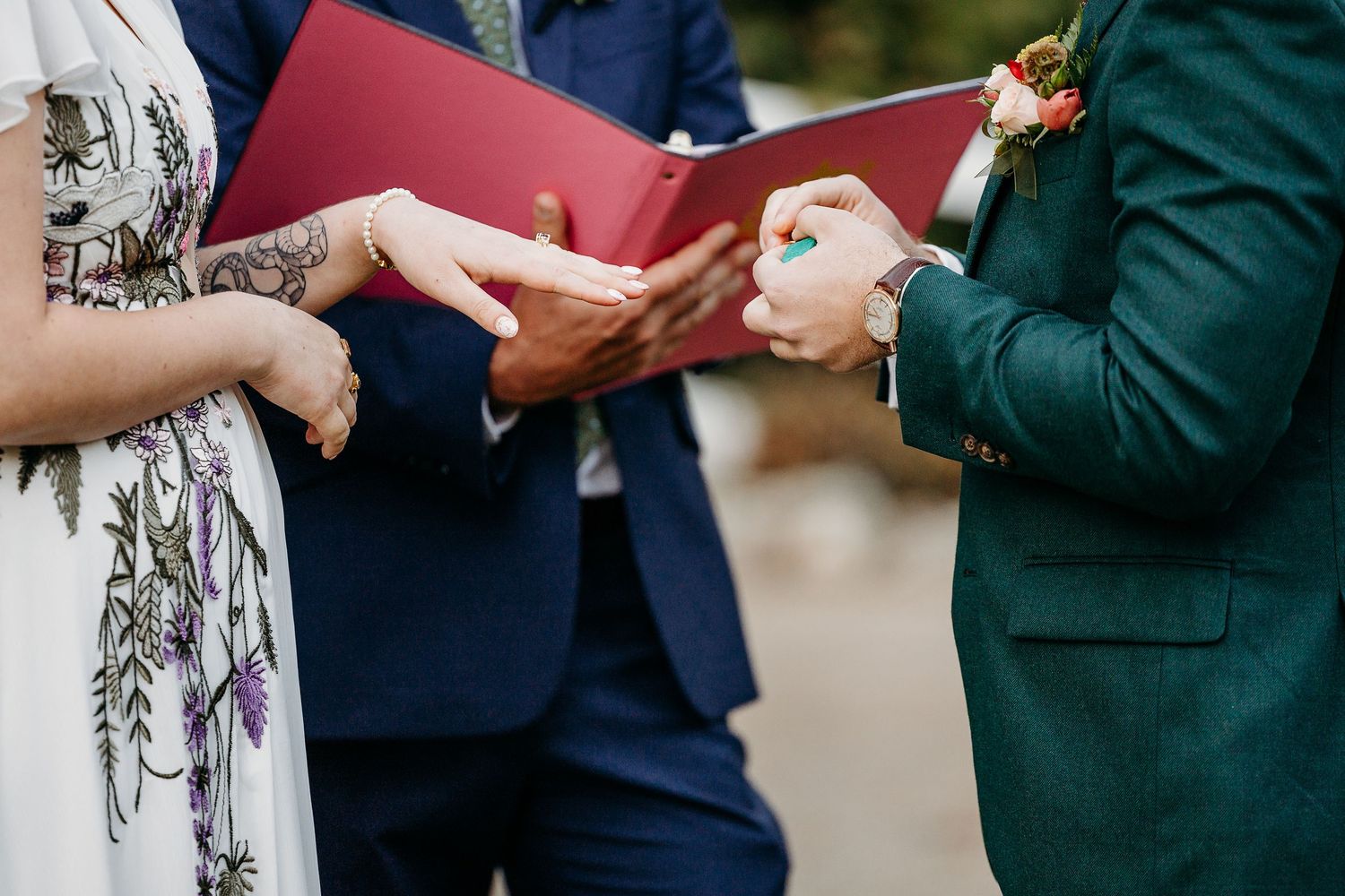 Wedding ceremony detail showing hands exchanging rings.