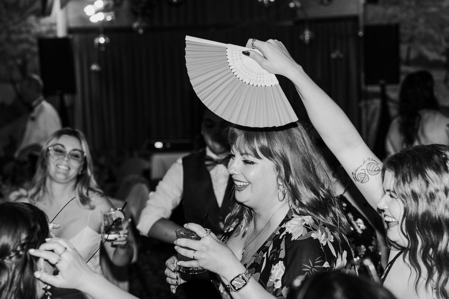 Wedding reception guests dancing and celebrating with paper fans on the dance floor.