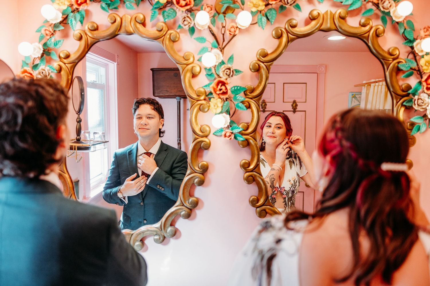 Wedding venue decorated with ornate gold mirrors and pink walls with string lights.