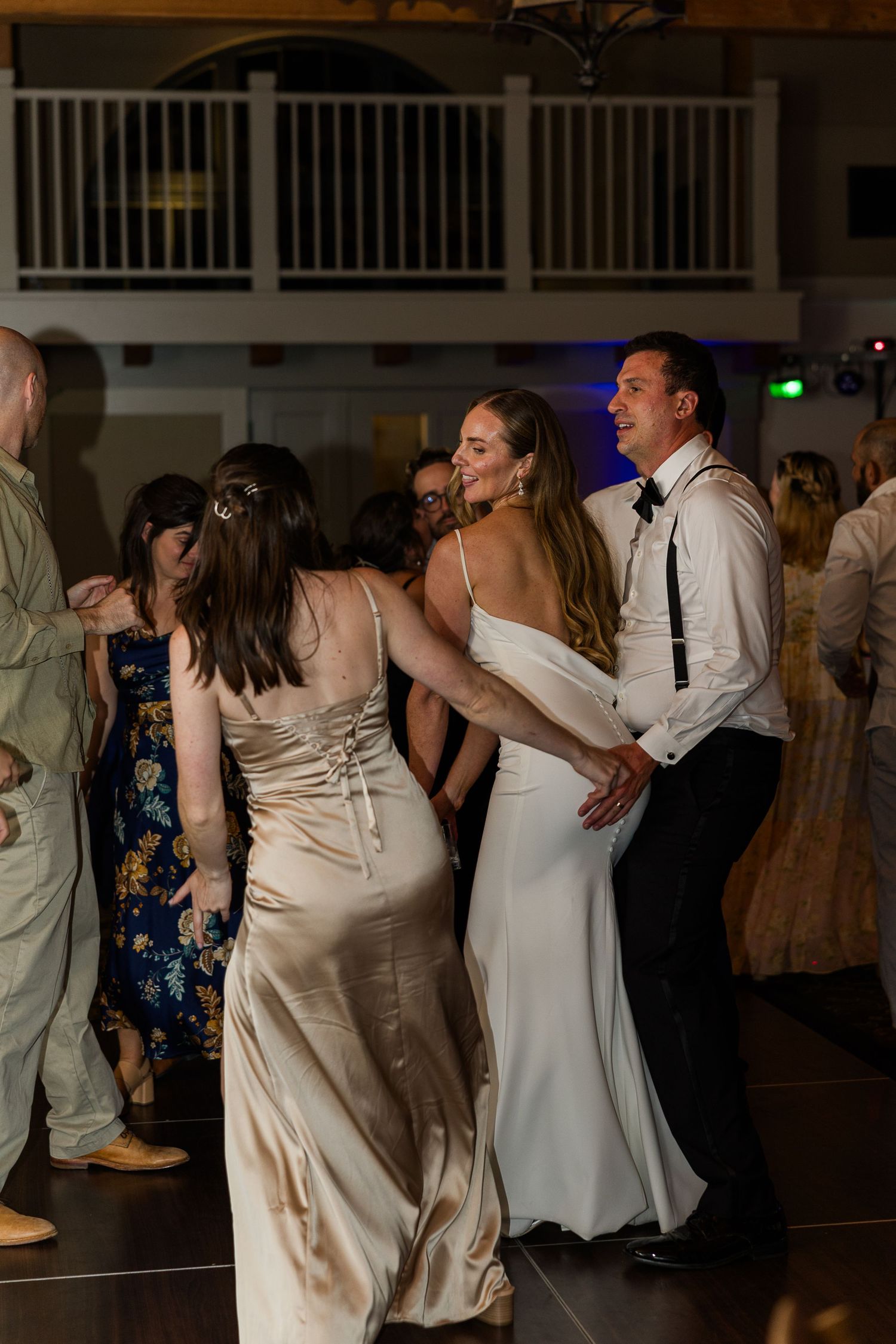 Wedding guests dancing and celebrating on a reception dance floor.